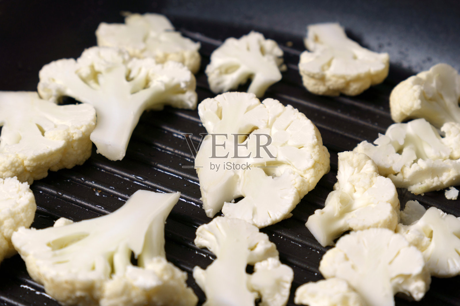 把生菜花片放在煎锅里。烹饪菜花牛排。烧烤锅，素食有机食品。照片摄影图片