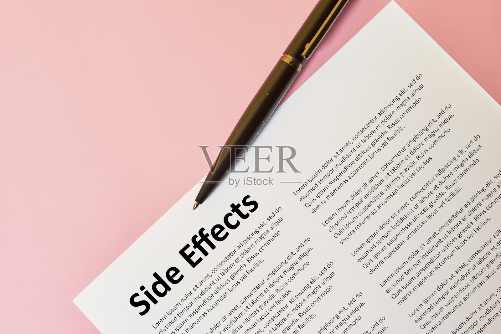 一篇论文的俯视图，标题为“副作用”，粉红色背景上有一支笔照片摄影图片