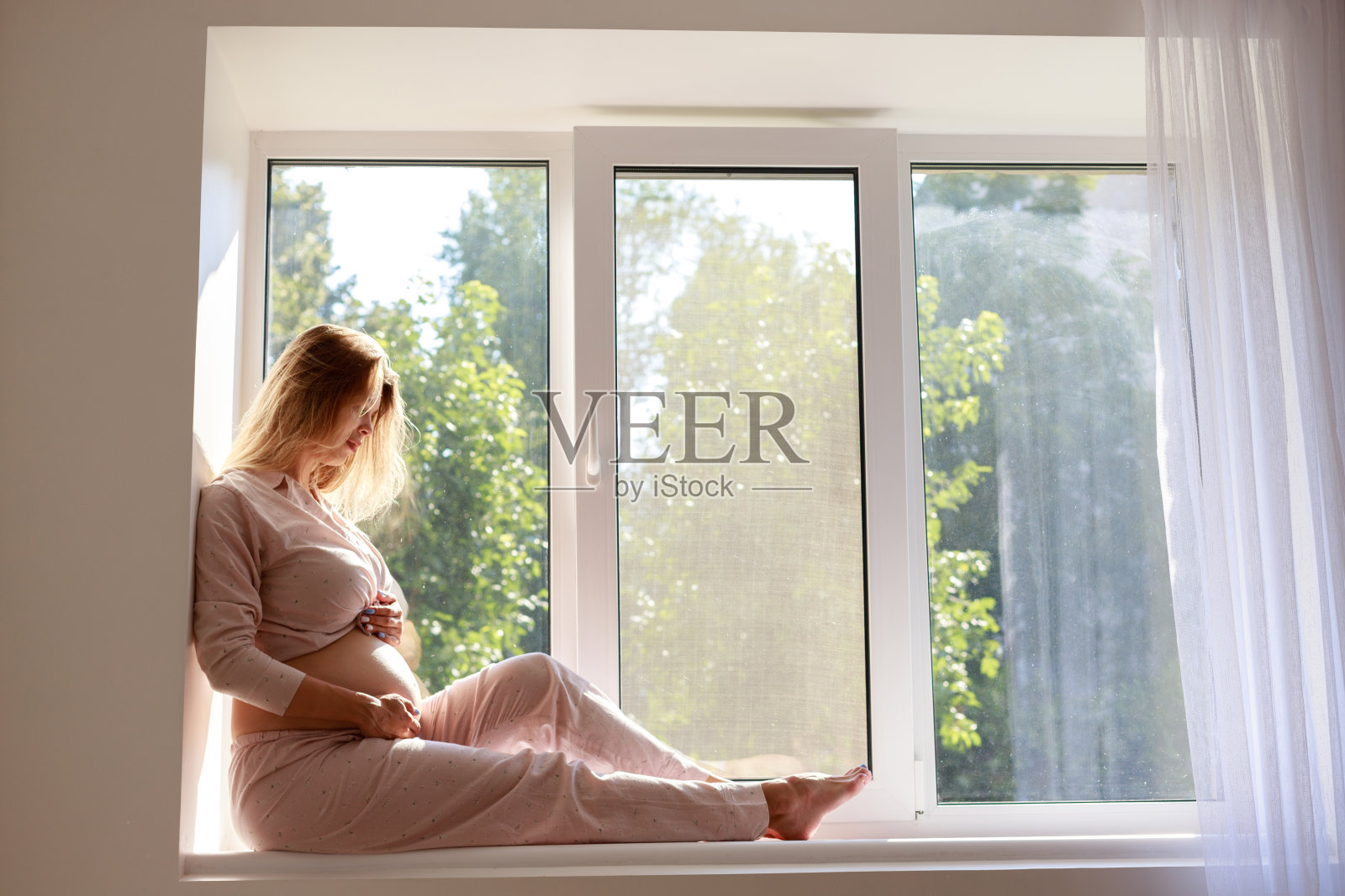 年轻漂亮的孕妇坐在窗户上照片摄影图片