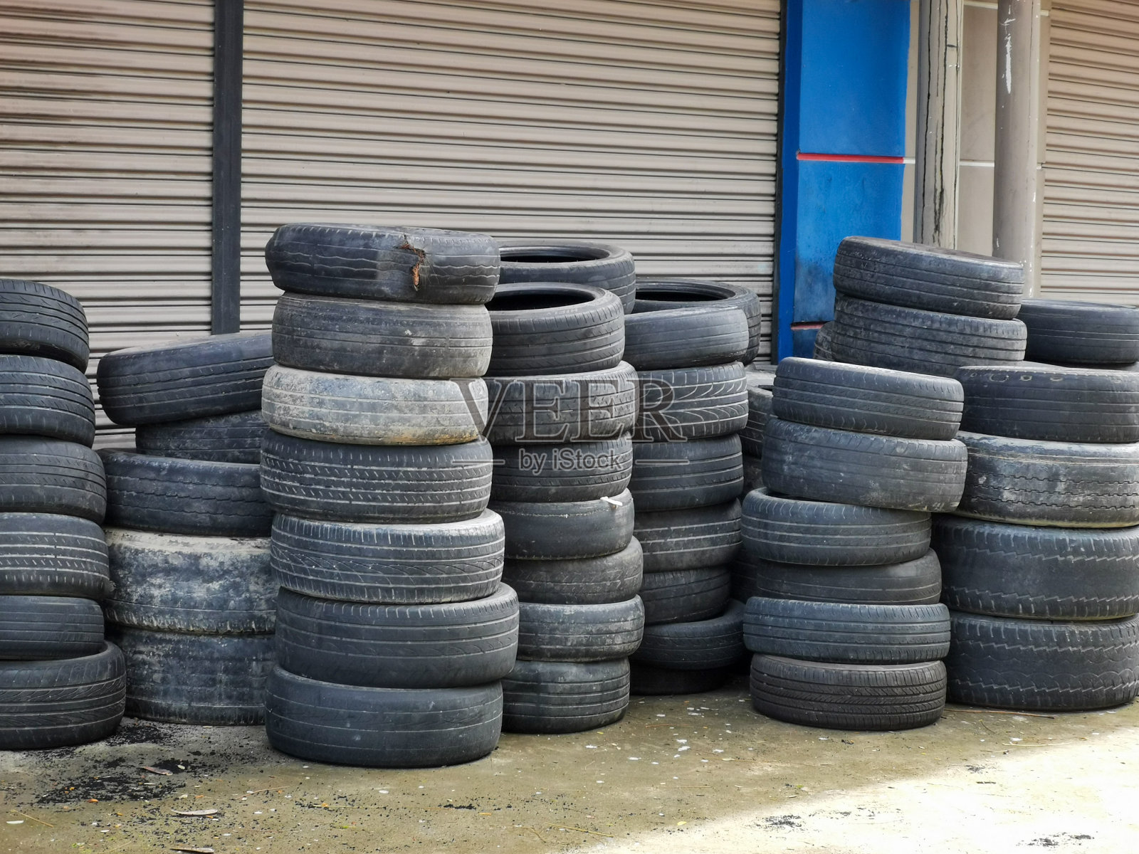 车间混凝土地板上堆放着旧轮胎。照片摄影图片
