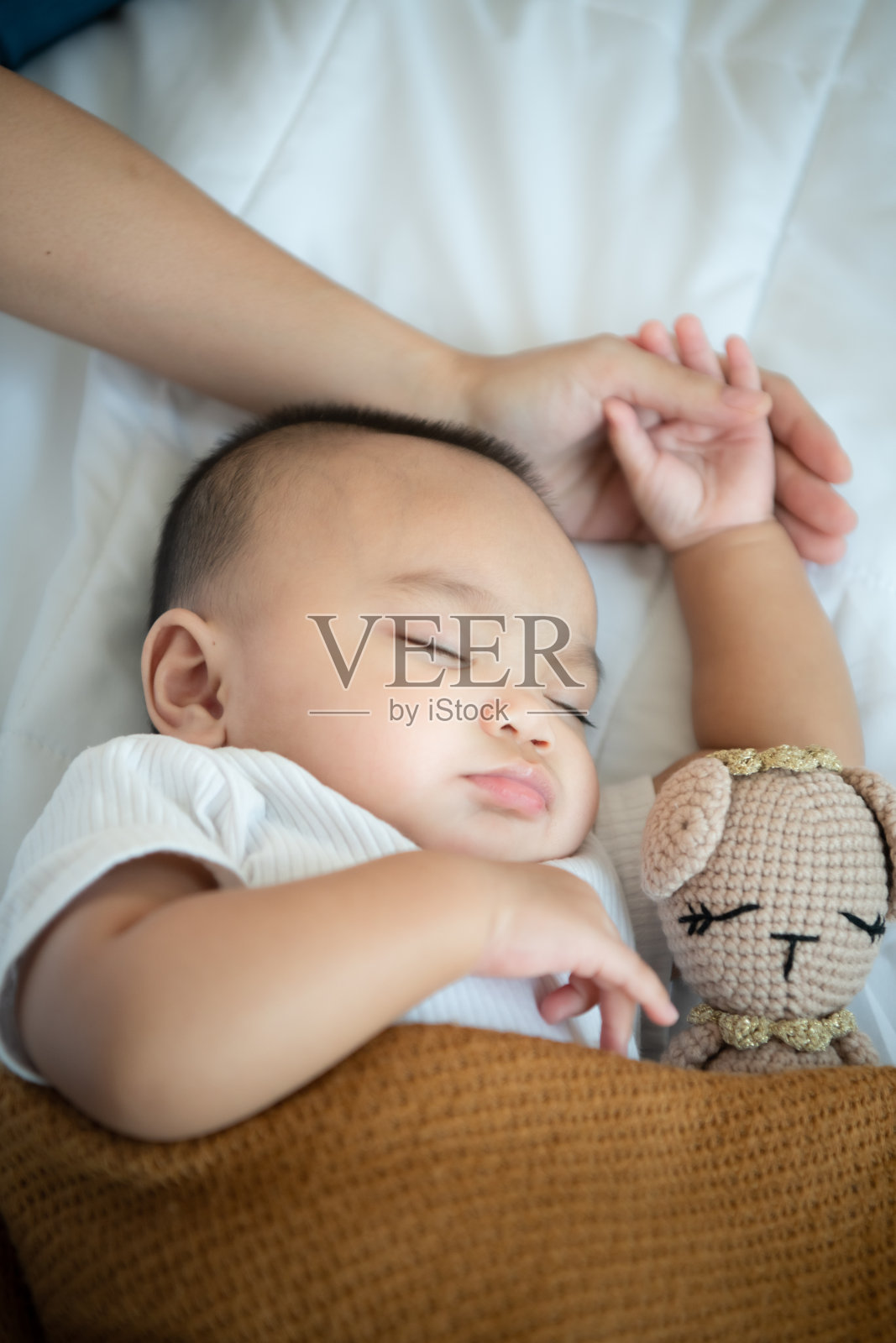 在白色的卧室里，年轻的母亲抱着刚出生的孩子哄他入睡照片摄影图片