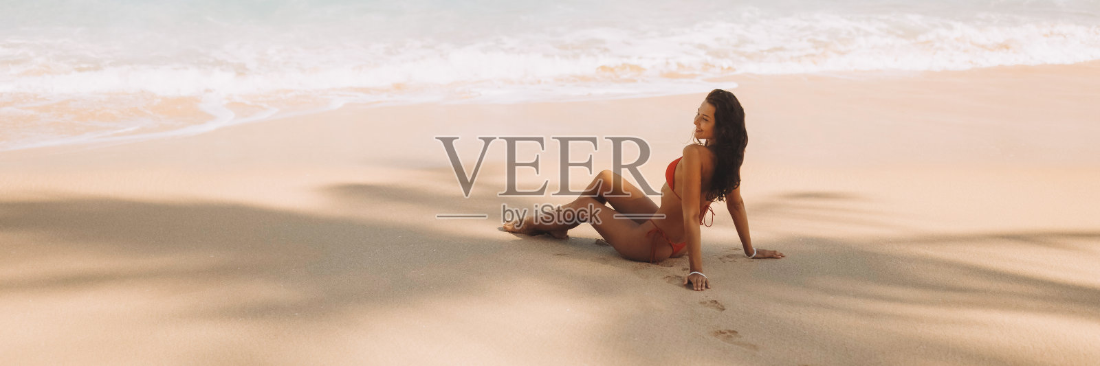 比基尼海滩女孩在红色泳衣在热带海岸棕榈树树荫下在海上度假照片摄影图片