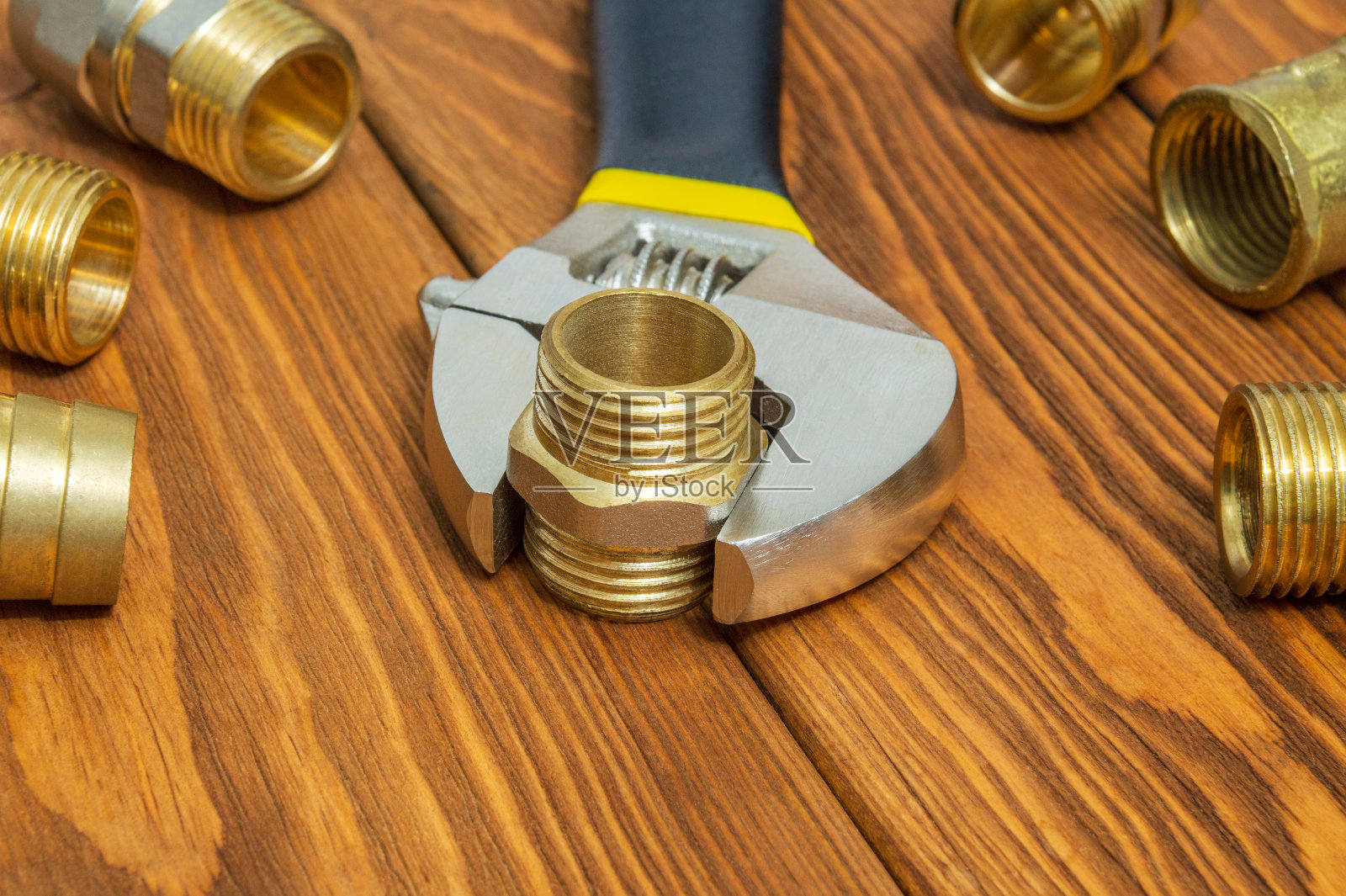 在维修或更换备件期间，老式木板上的管道黄铜配件和可调扳手特写照片摄影图片