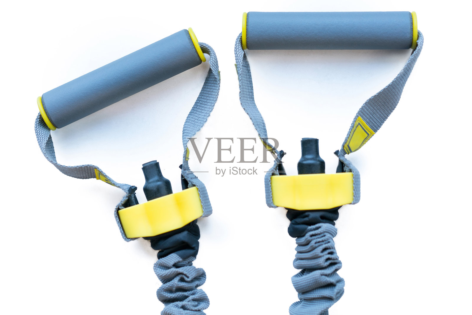 两个灰色和黄色的乳胶阻力带手柄在尼龙安全套筒中卷曲。运动。设备。健身房。培训。硫氧还蛋白。首页橡胶膨胀机照片摄影图片