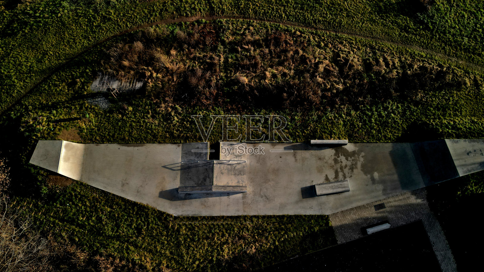 为滚轴运动设计了混凝土水泥地面滑板公园，设有混凝土滑板障碍物。除了自由式自行车外，不允许骑自行车。冬日清晨的日出，高高在上照片摄影图片