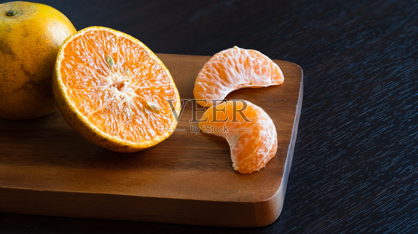 新鲜有机陈皮(将军)橙果。把橙子切成两半，切成片放在木砧板上。照片摄影图片