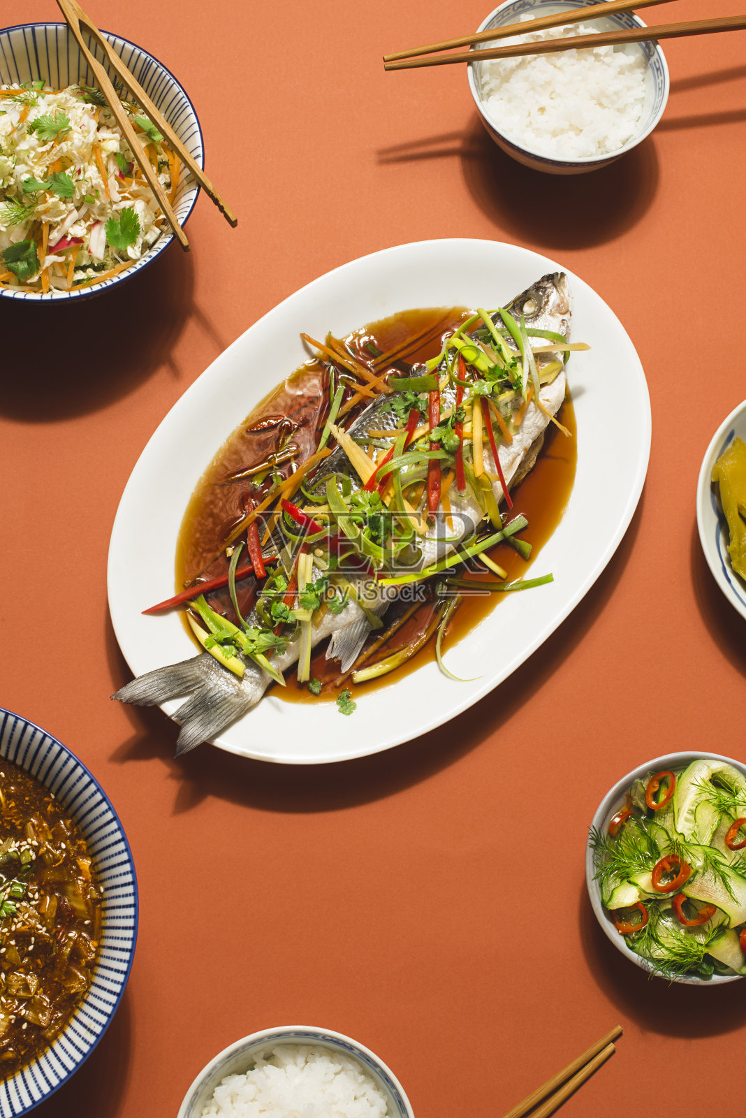 中国新年餐桌的粤式食谱。海鲈鱼或斯皮格拉鱼配姜蒸，红辣椒酱配大白菜，传统的辣汤和米饭照片摄影图片