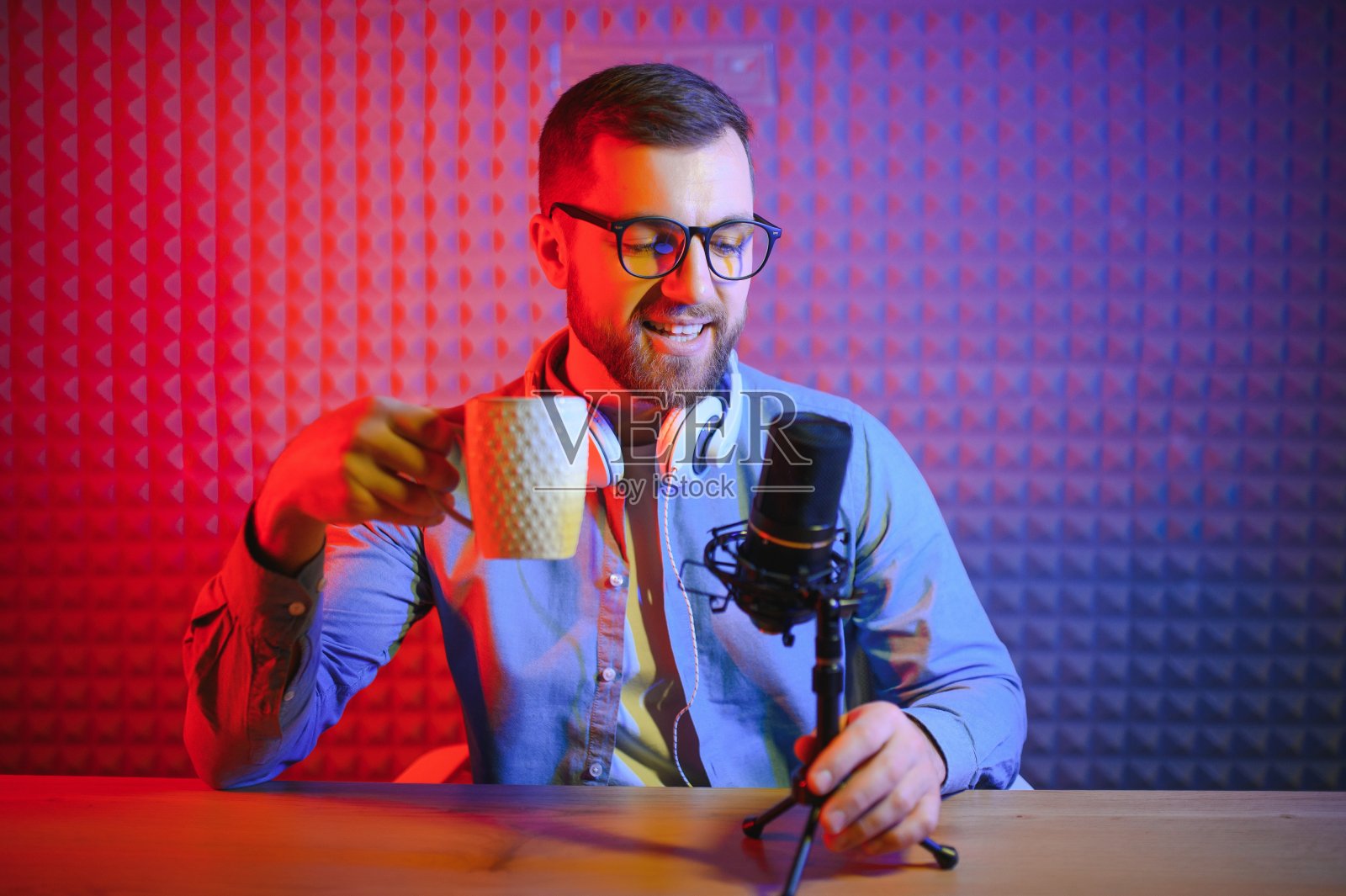 一名视频博主在他的工作室录制内容。视频博客的主人是一个年轻人，他非常热衷于给他的订阅者讲故事。照片摄影图片