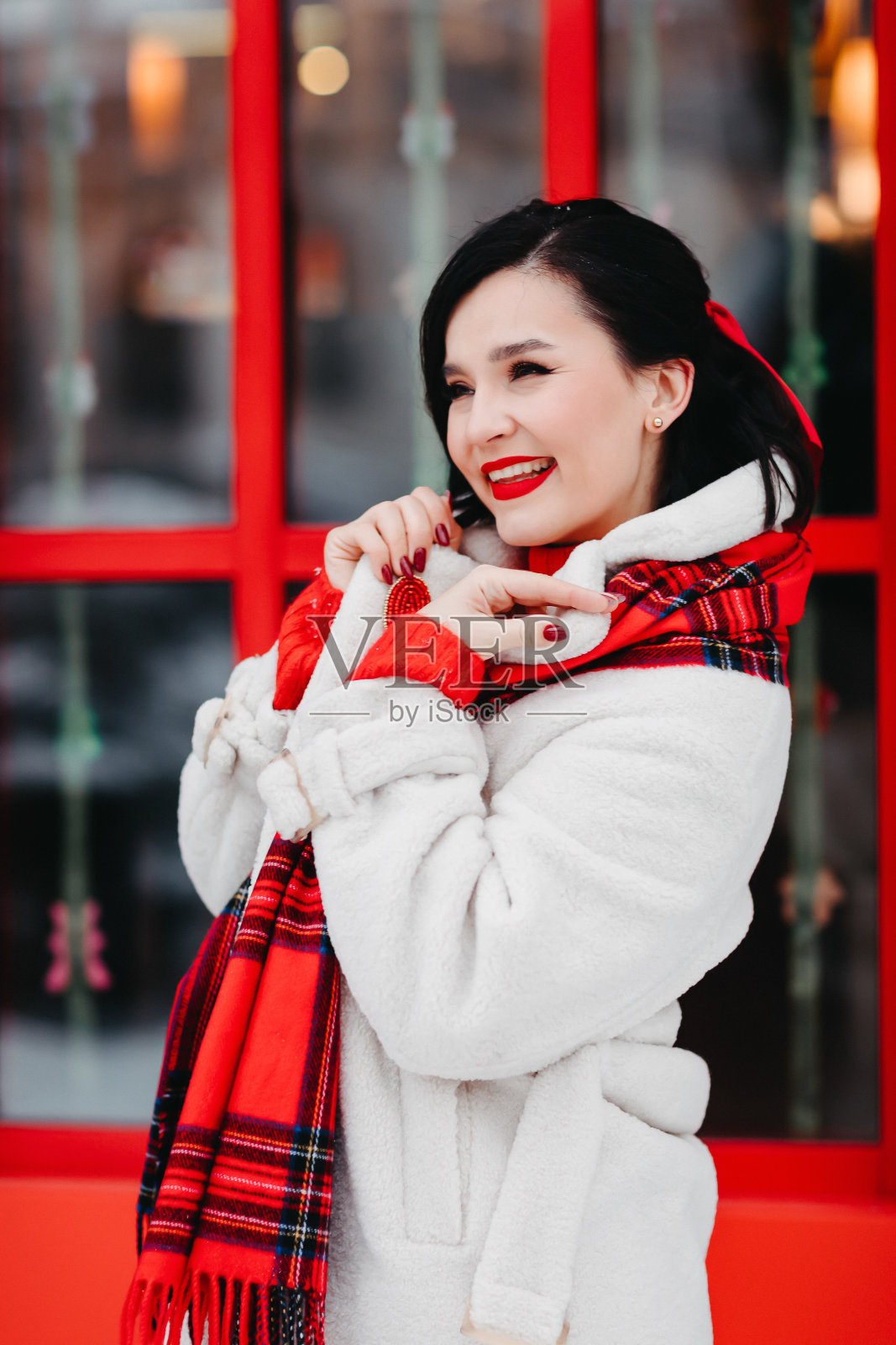 一个冬季小镇的街道上有一个迷人的黑发女人。照片摄影图片