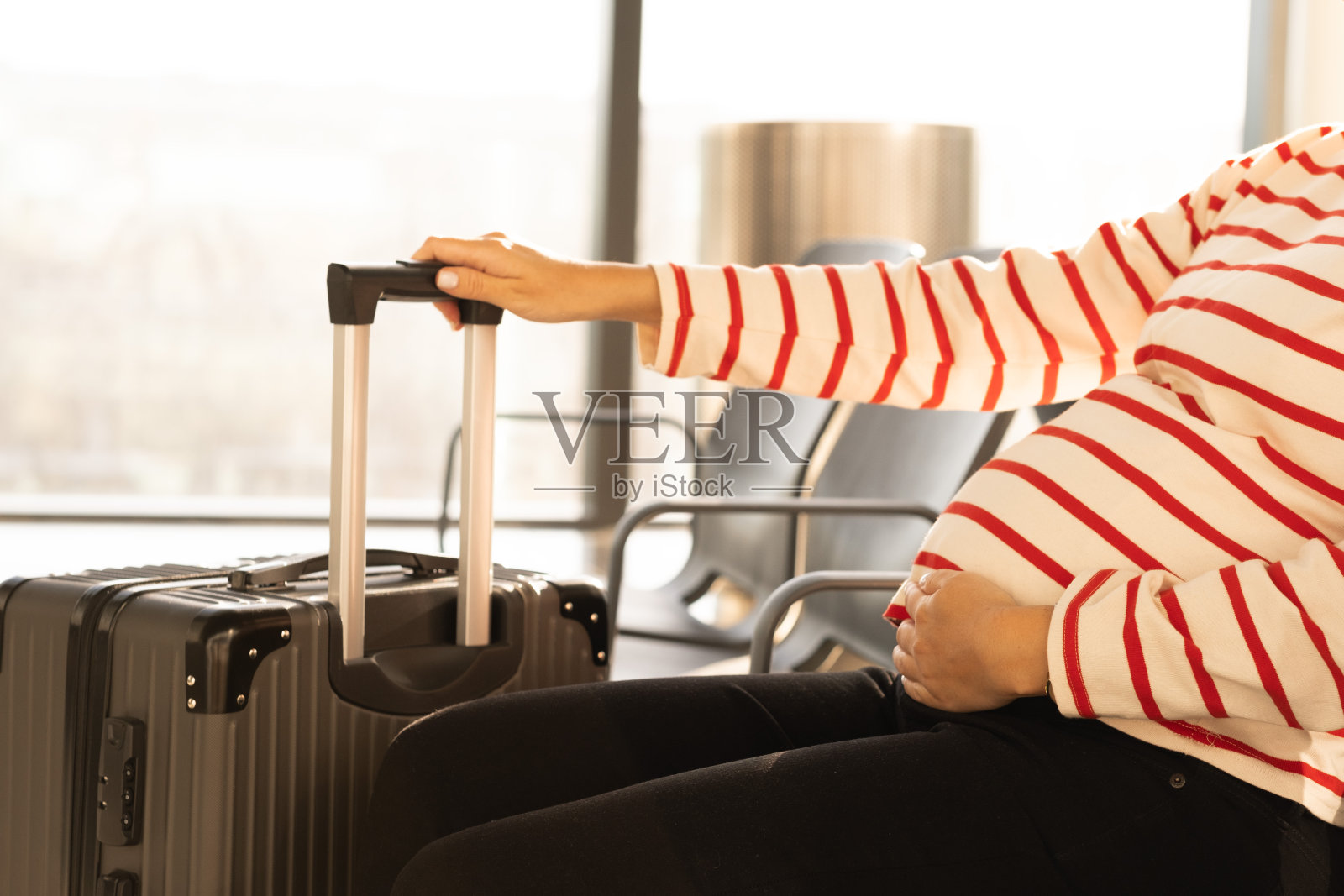 不明身份的白人孕妇带着行李在机场等待办理登机手续。怀孕期间安全飞行，旅行的概念。本空间照片摄影图片