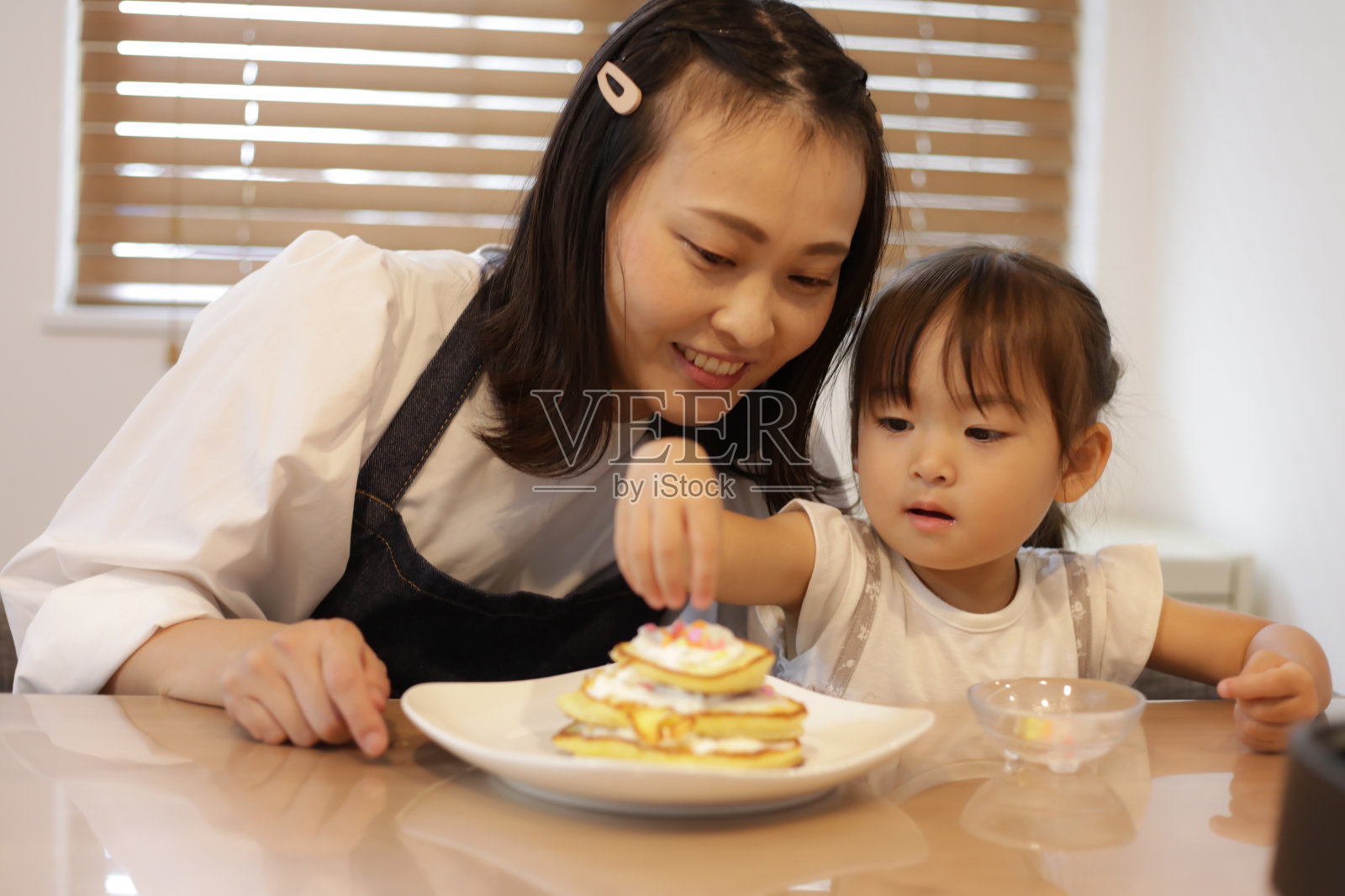 父母和孩子在热蛋糕上放配料照片摄影图片
