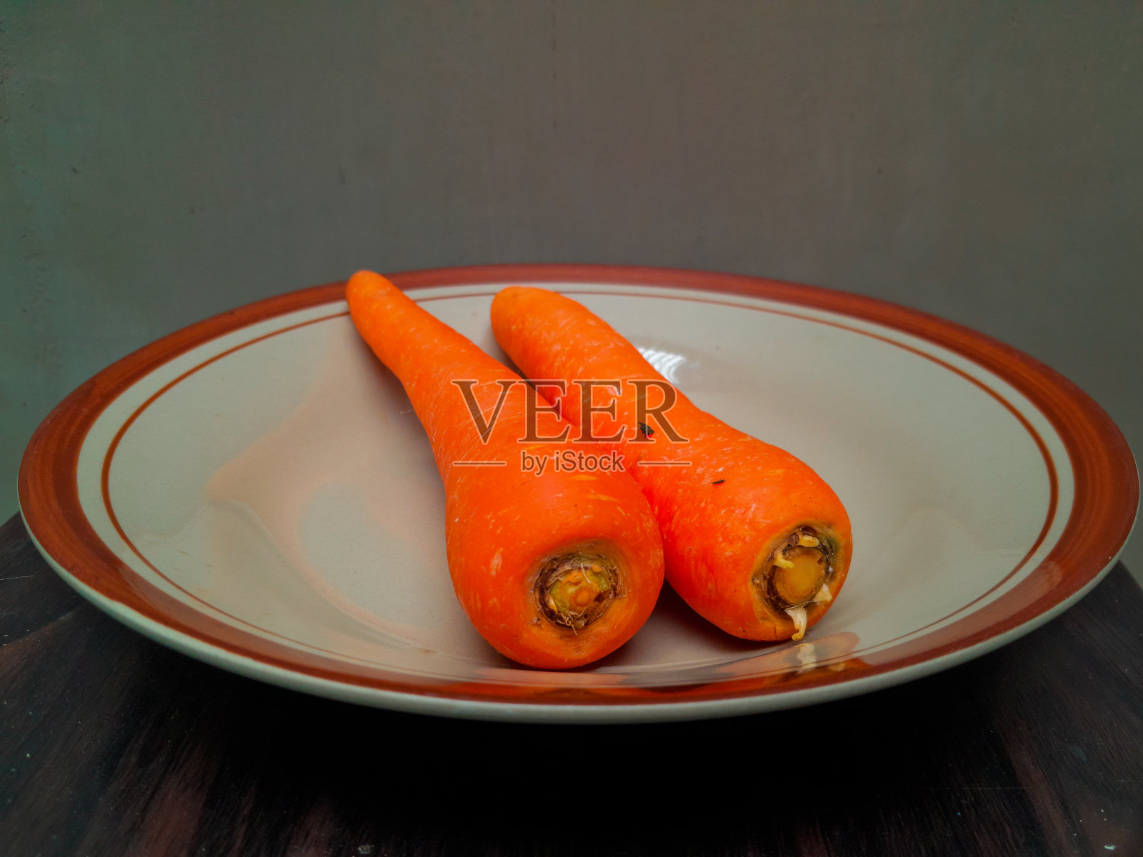 一些橙色的胡萝卜放在一个棕色的陶瓷盘子里照片摄影图片