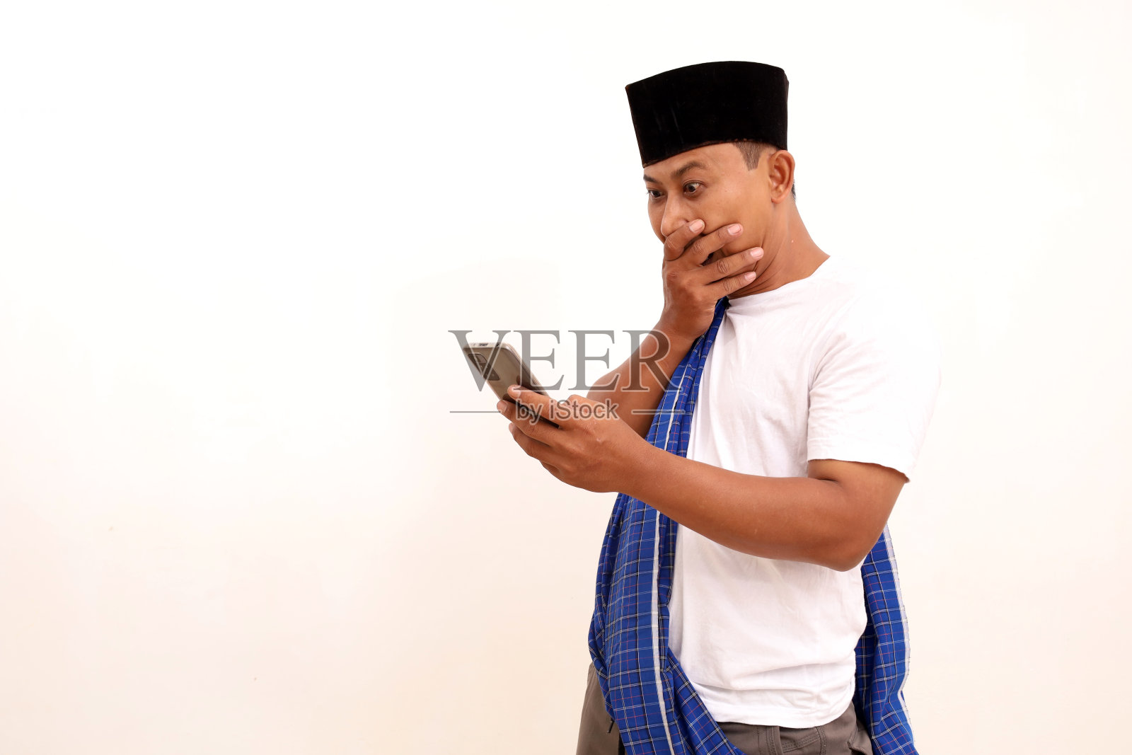 高兴和惊讶的亚洲人看着他的手机。白色背景隔离照片摄影图片