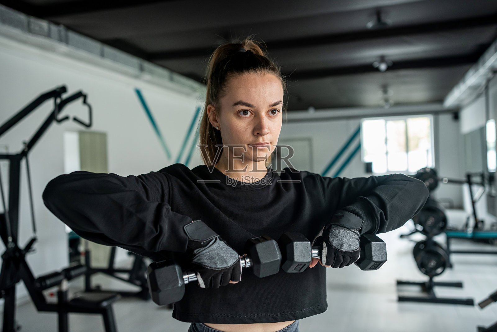近距离年轻女子训练肌肉在健身房里的健身机。照片摄影图片