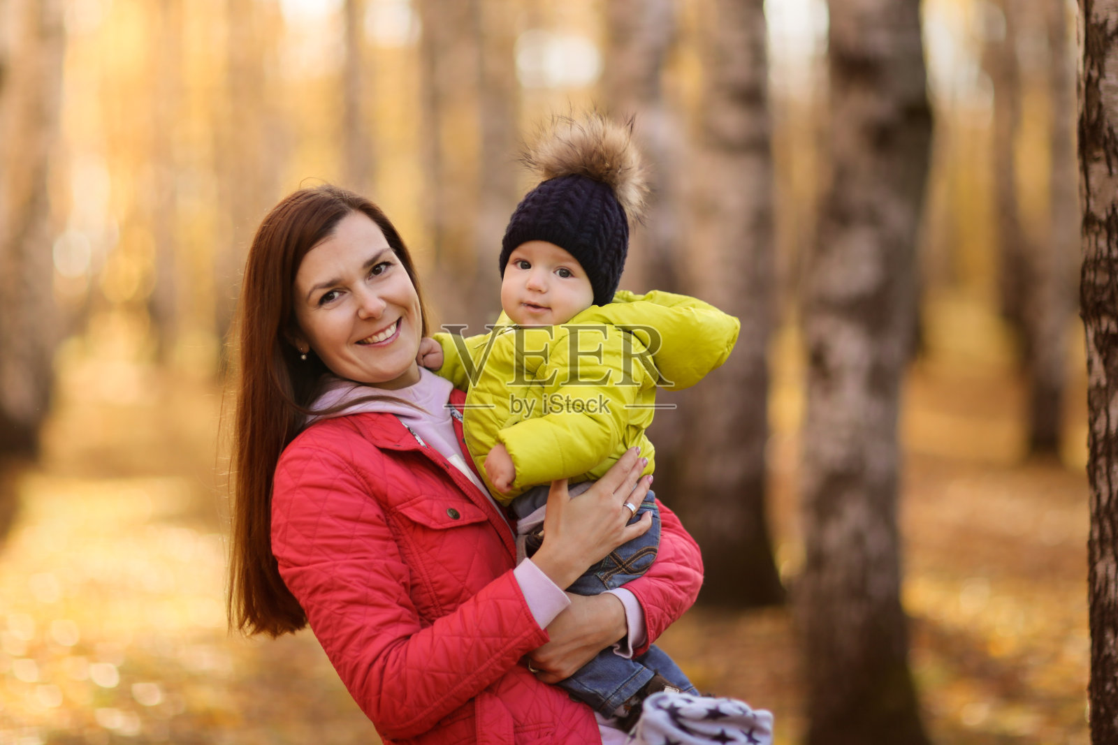 黑发妈妈抱着宝贝儿子，美丽秋色照片摄影图片