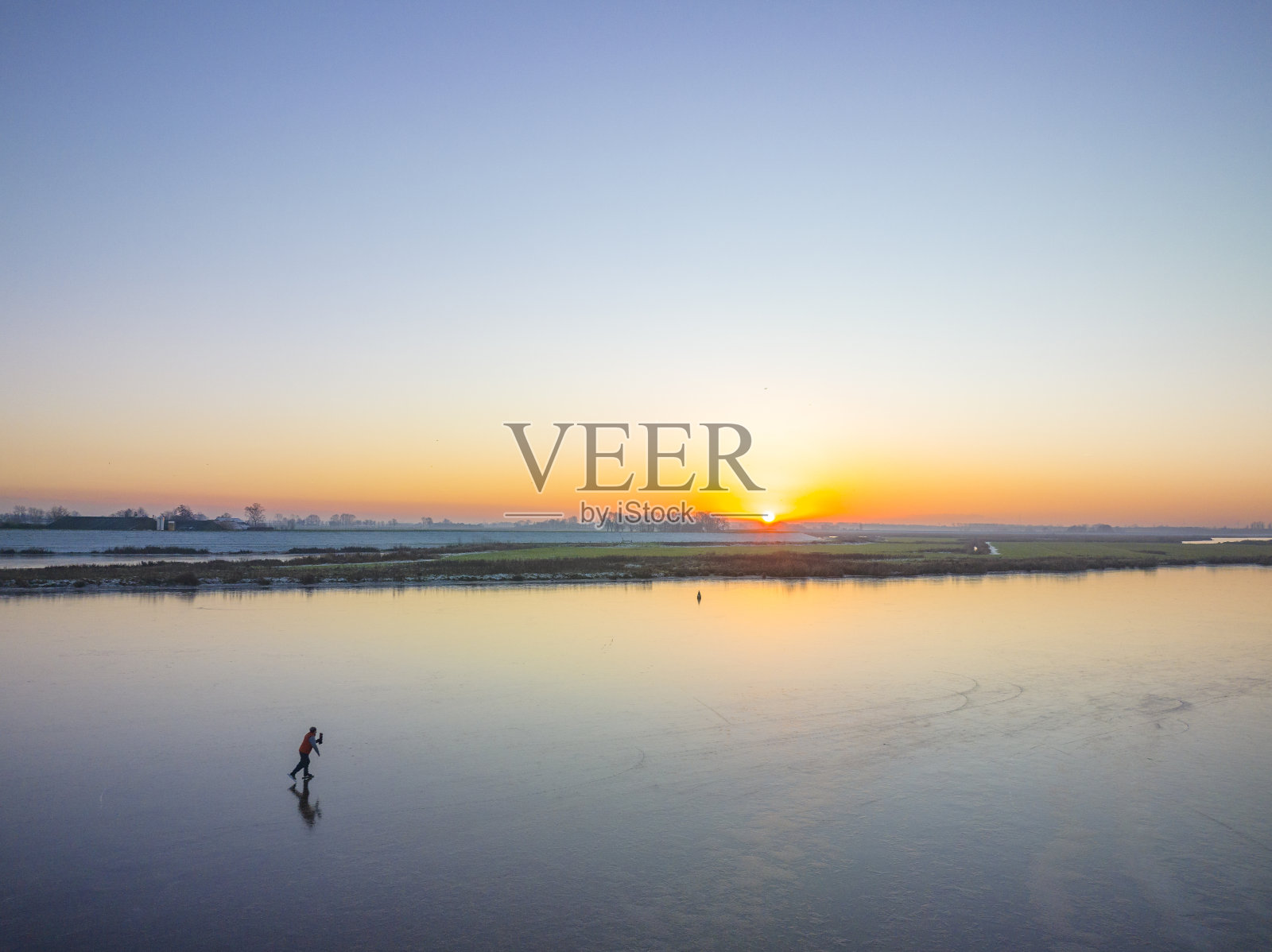 在美丽的冬日夕阳下，荷兰的湖面上滑冰照片摄影图片