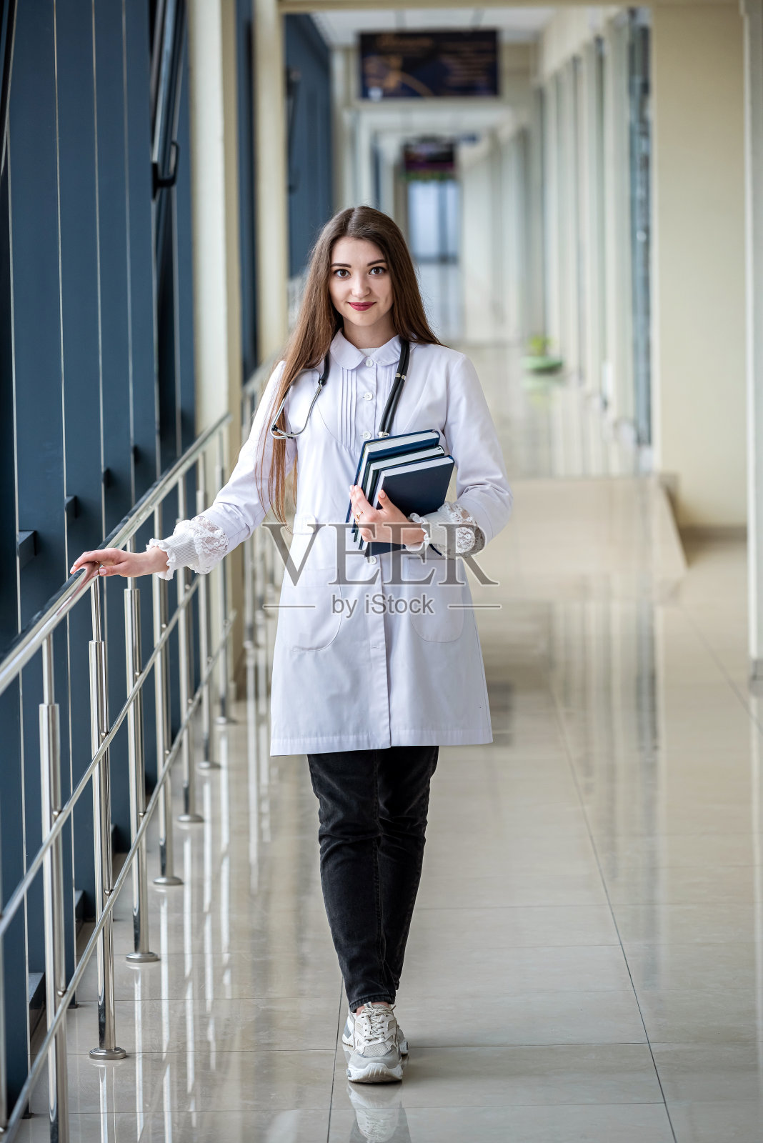 穿着特殊制服的年轻女牙医站在走廊上，微笑着她理想的牙齿照片摄影图片