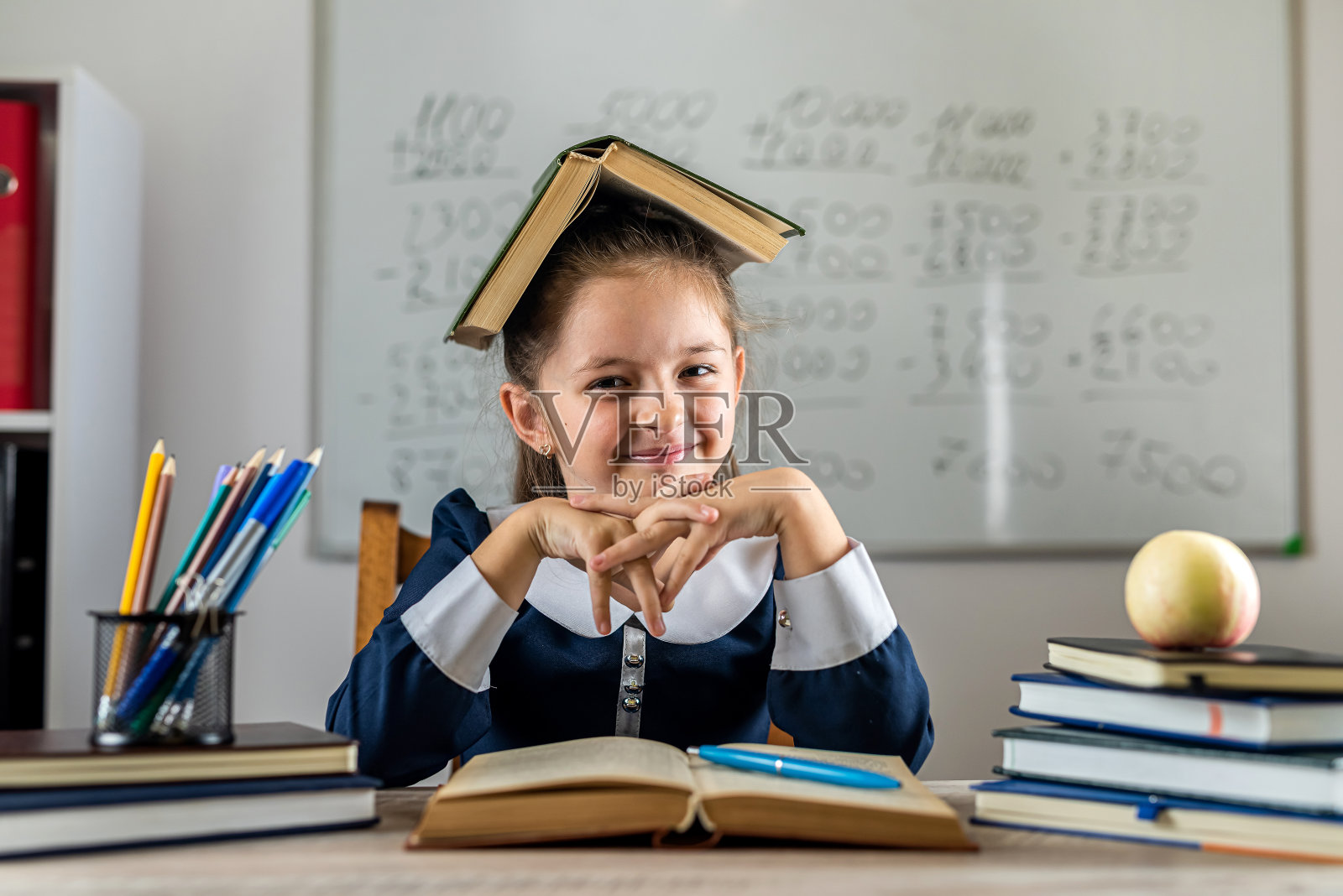 可爱勤劳的孩子正坐在室内的一张桌子旁。照片摄影图片