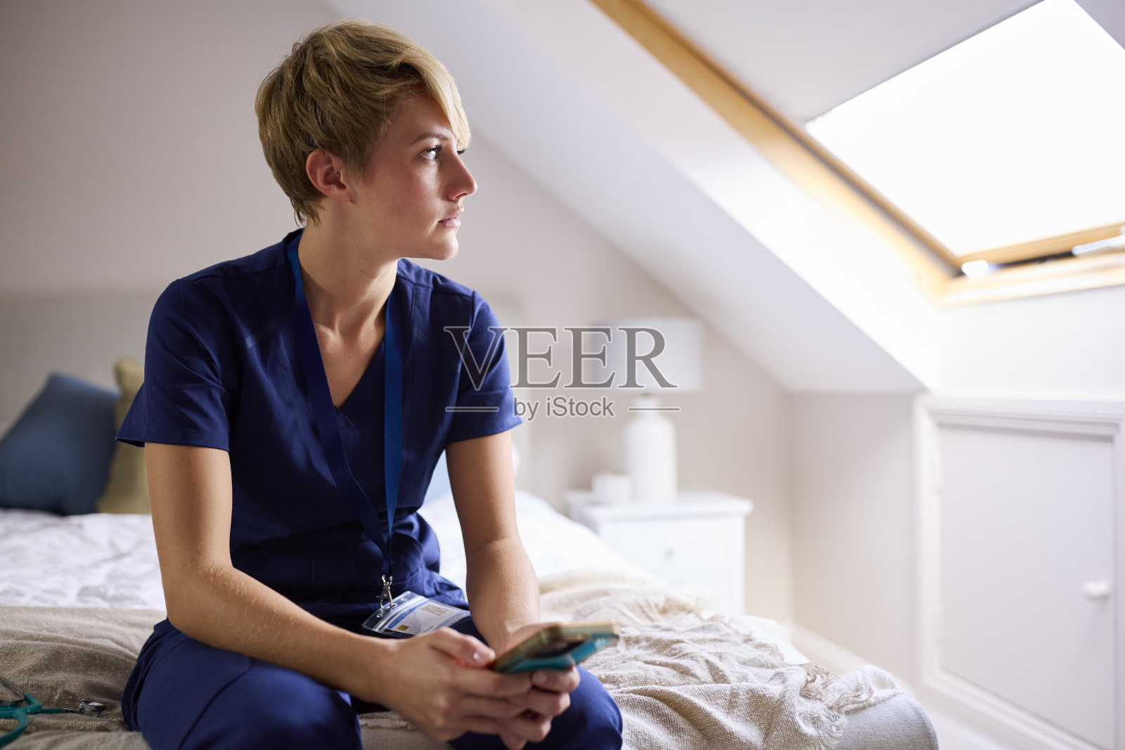 穿着医用工作服坐在地板上看手机的女人照片摄影图片