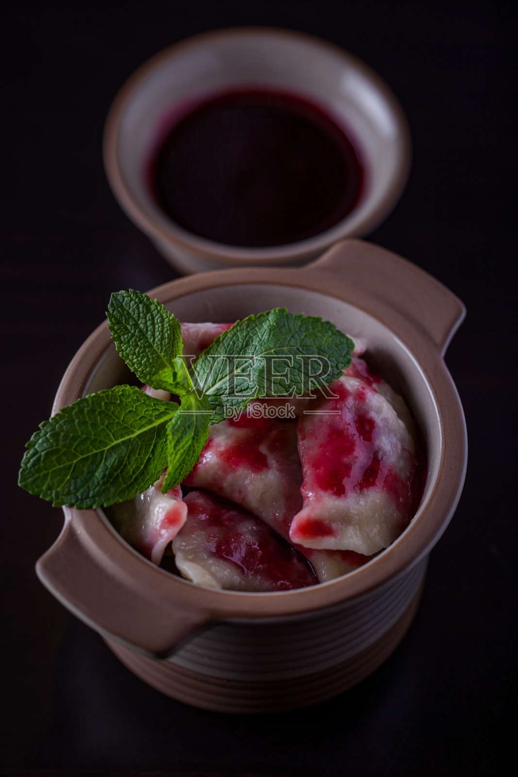 黑色背景的樱桃、薄荷和果酱饺子。垂直方向照片摄影图片