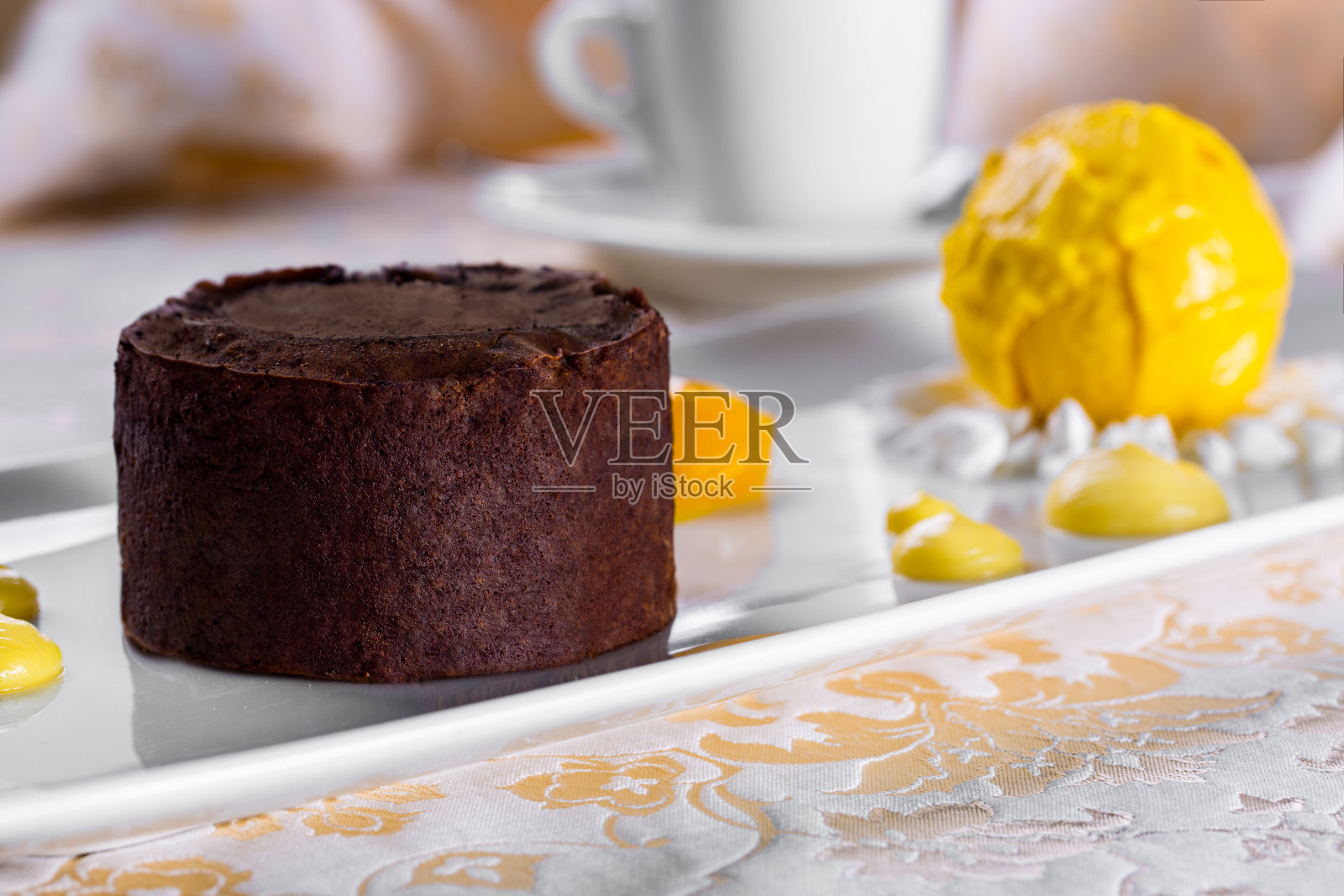 巧克力软糖和一勺黄色冰淇淋，奶油和蜜饯水果放在一个白色的盘子里。水平方向照片摄影图片