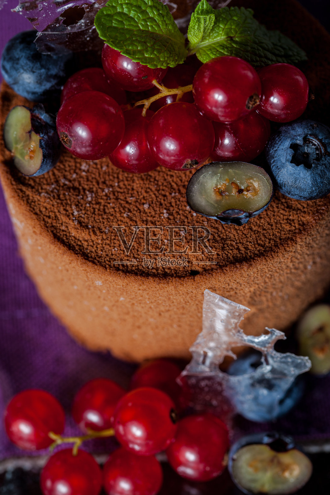 甜点用水煮可可翻糖，红醋栗和蓝莓在紫色糖的背景。垂直方向照片摄影图片