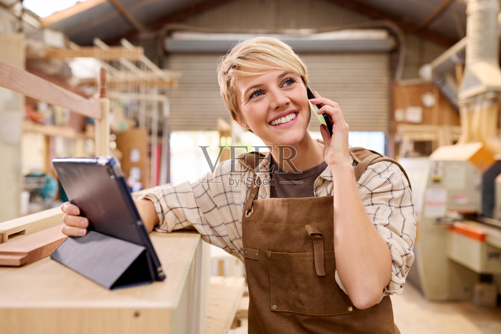 女学徒拿着平板电脑在家具车间当木匠打电话照片摄影图片