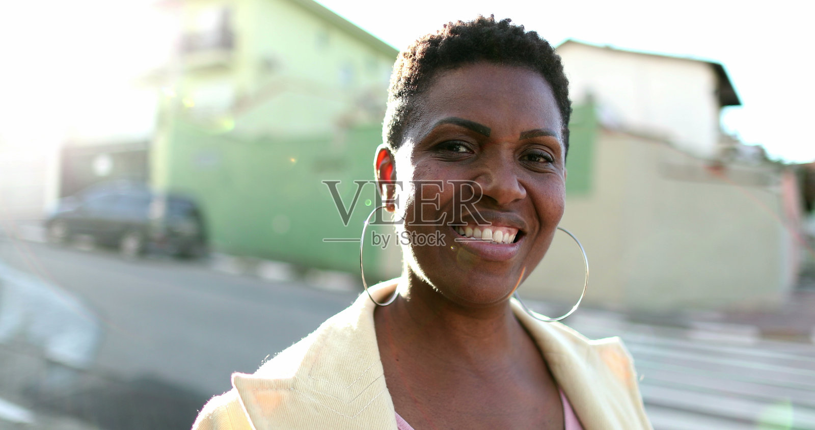 非洲妇女站在太阳耀斑微笑外面。黑人妇女在街上看着相机照片摄影图片