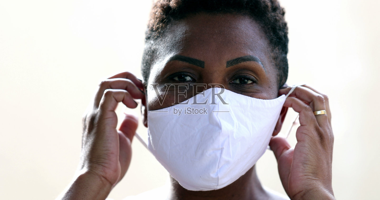 非洲妇女戴着新冠肺炎口罩，黑人女性看着镜头照片摄影图片