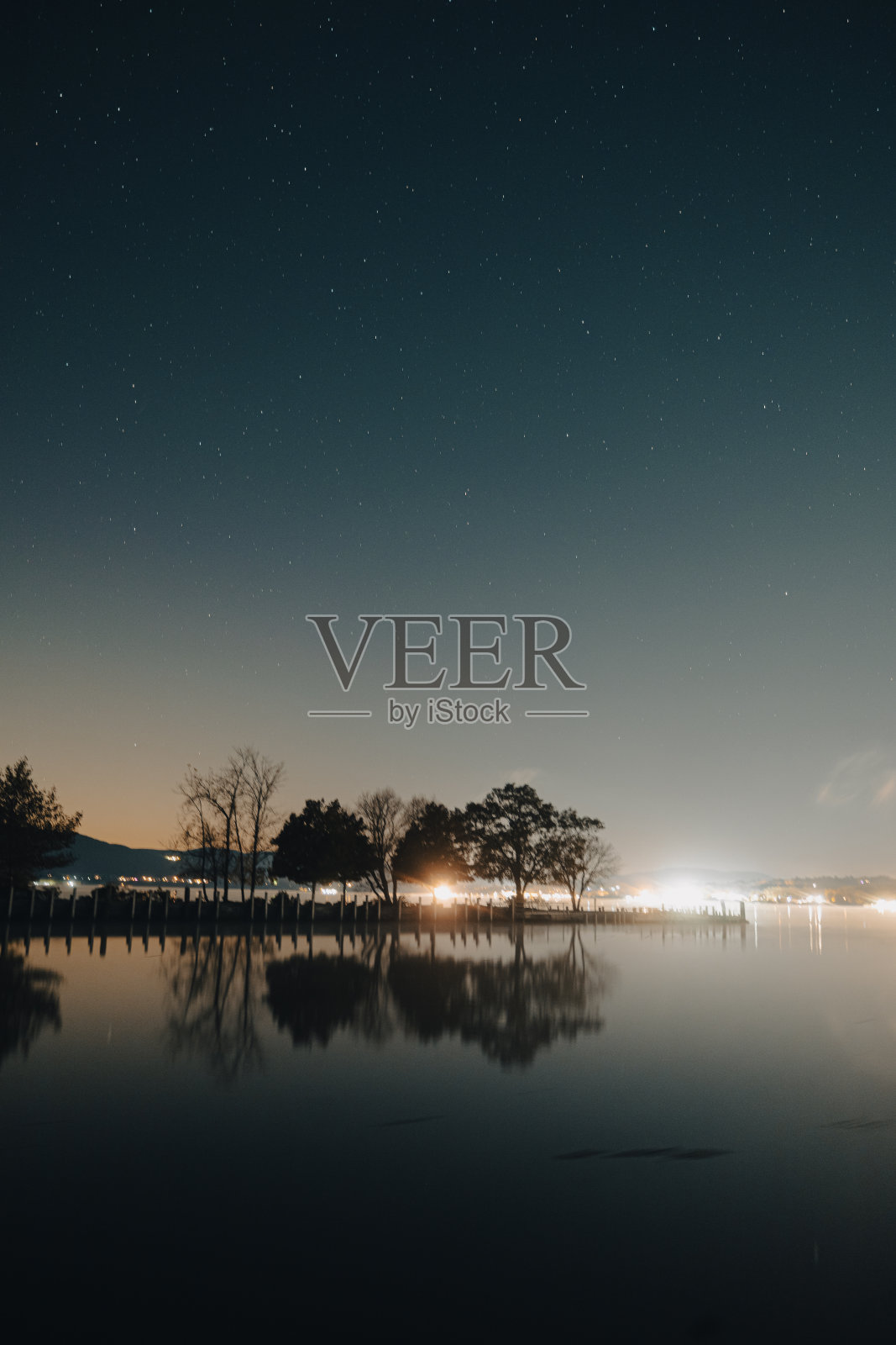 垂直拍摄的树木在日出时倒影在湖中照片摄影图片