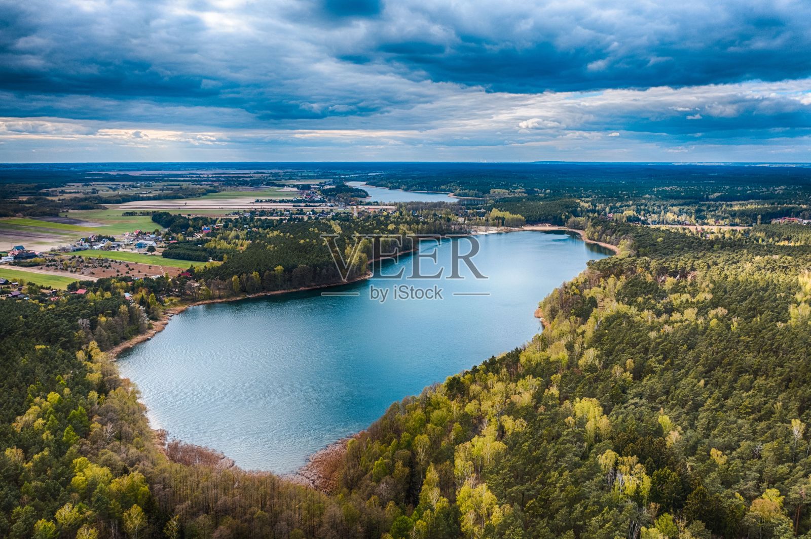 无人机拍摄的Rozalinowo湖被绿色景观包围，在多云的天空下有小房子照片摄影图片