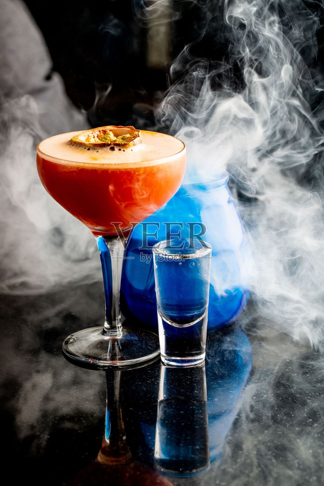 垂直拍摄的酒精鸡尾酒周围的烟雾反射表面。照片摄影图片