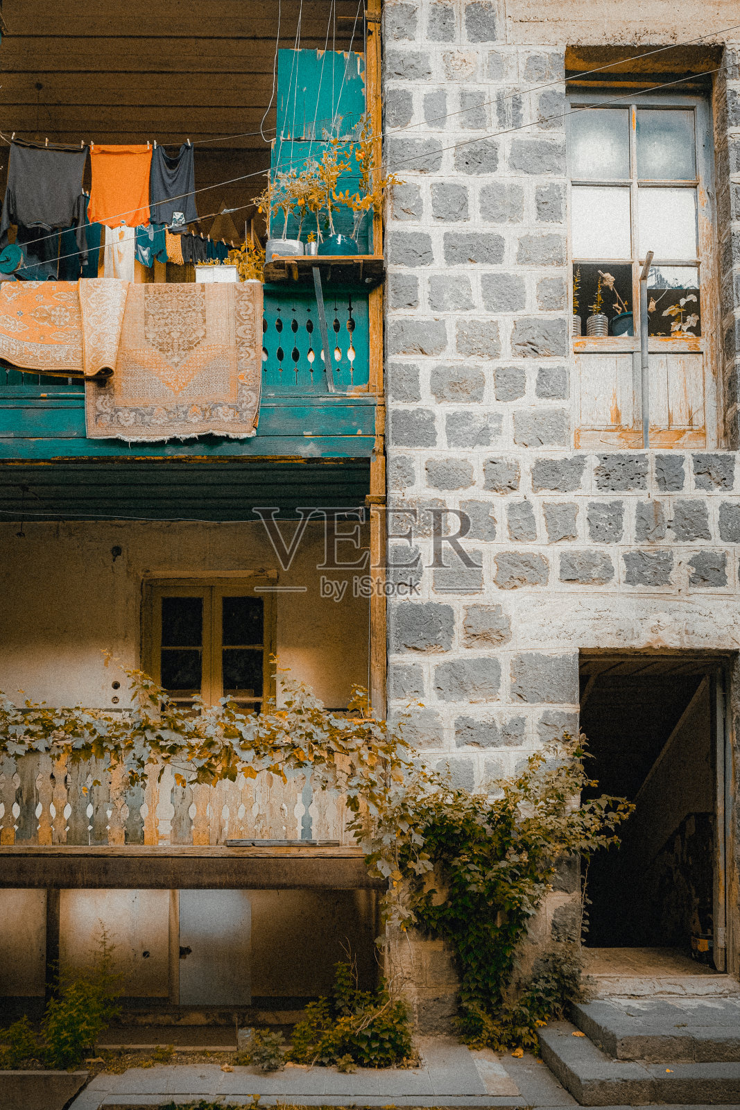 垂直拍摄的传统亚美尼亚建筑的正面阳台，悬挂的衣服和地毯照片摄影图片