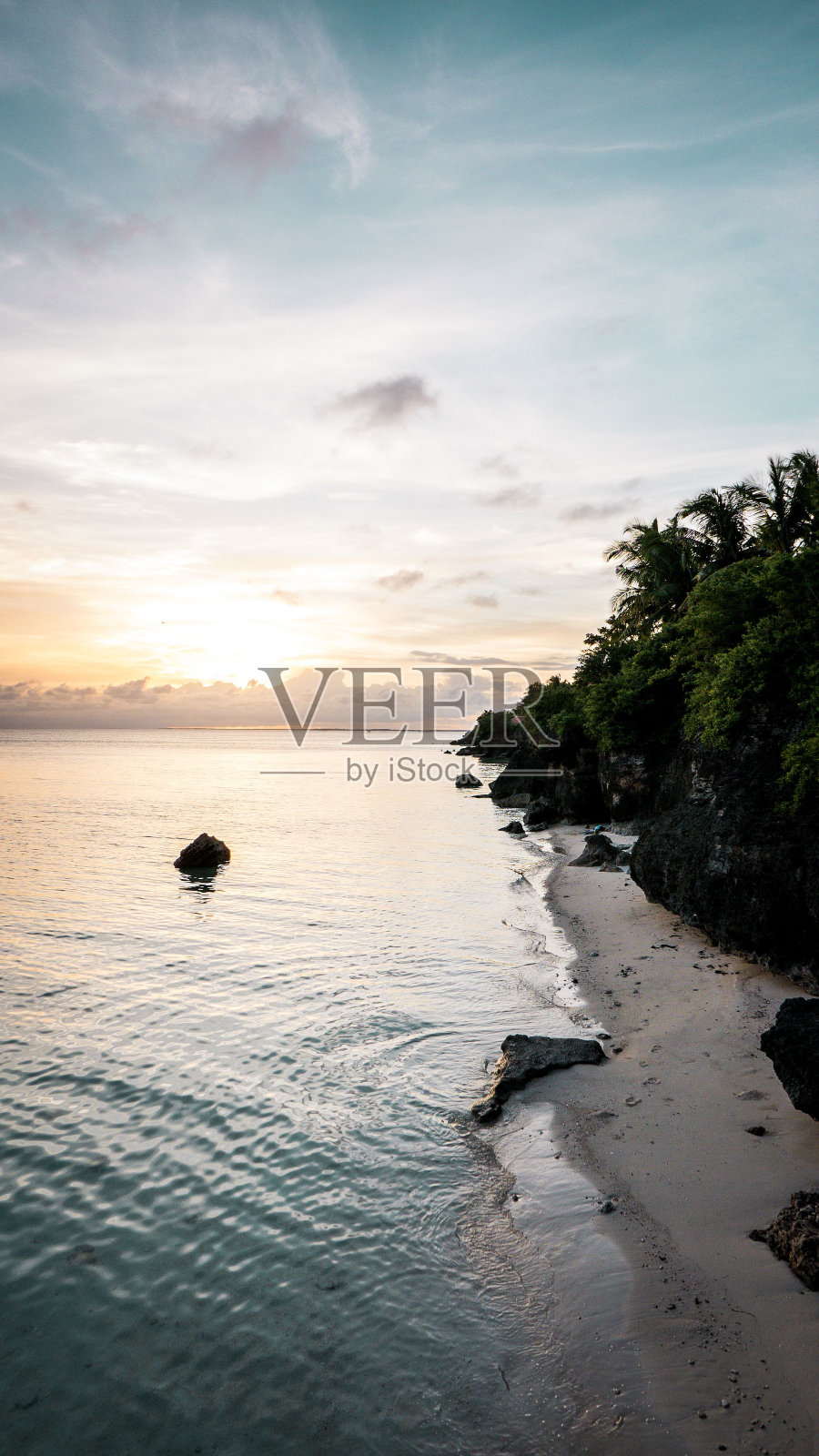 垂直拍摄平静的海水和沙滩在一个岛屿上，美丽的日出在地平线上照片摄影图片