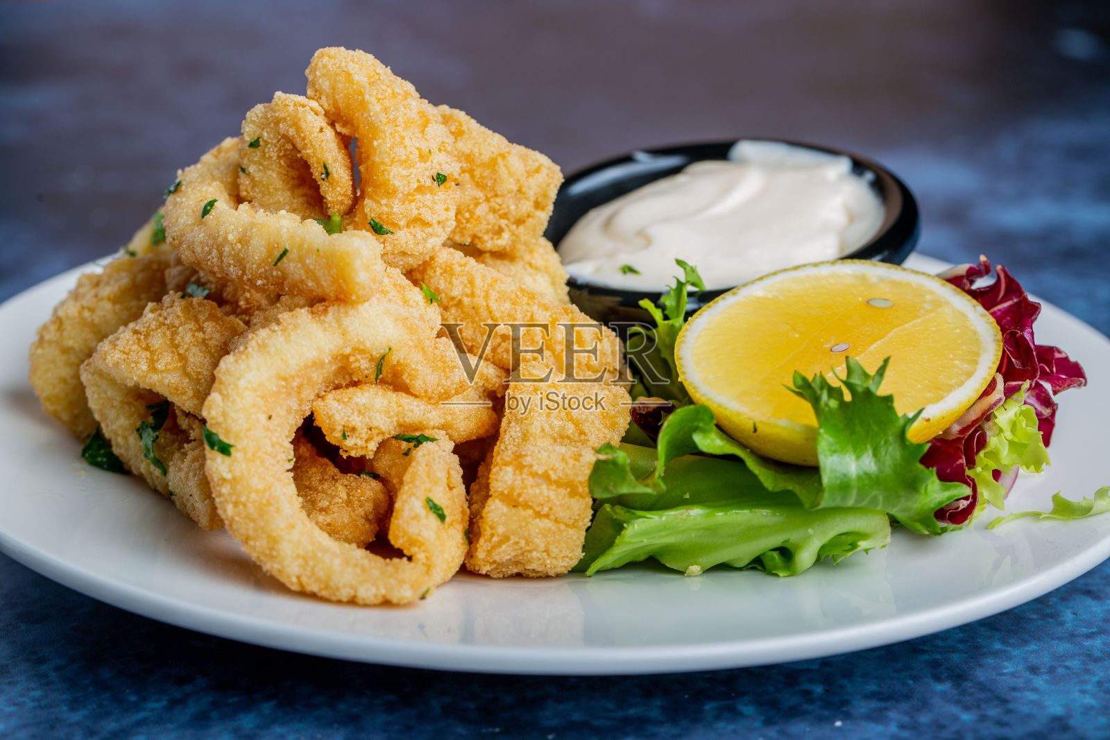 新鲜出炉的面包鱿鱼卷配柠檬，放在白盘子里照片摄影图片