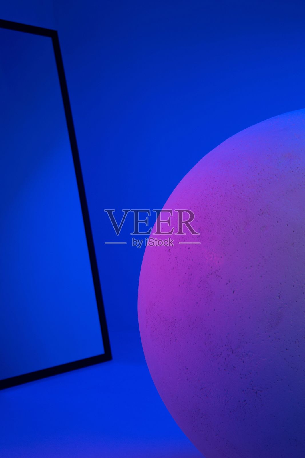 垂直拍摄的圆形石球被蓝色和紫色的霓虹灯照亮，对着镜子照片摄影图片