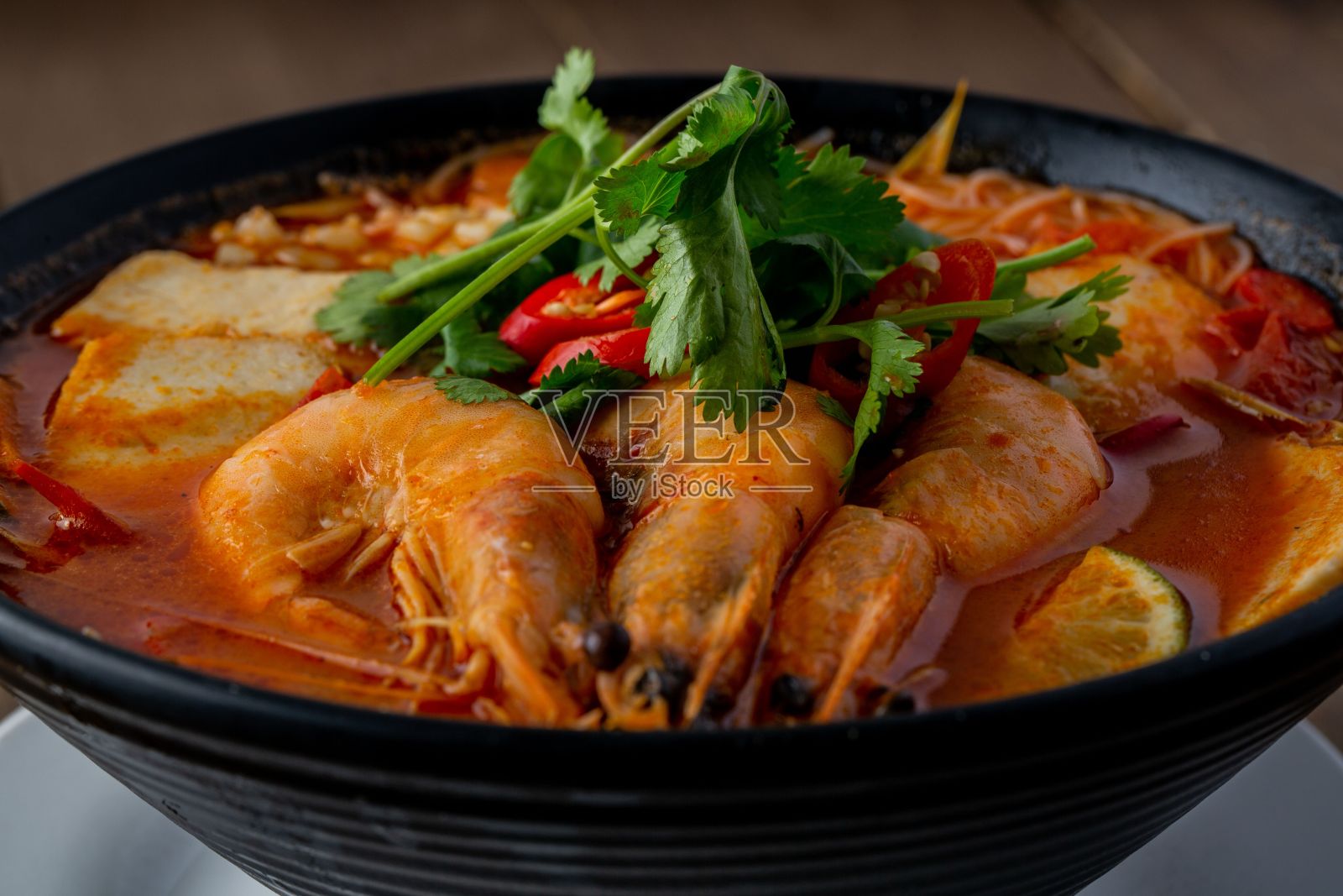 特写镜头的冬阴汤虾和装饰香菜在碗里照片摄影图片