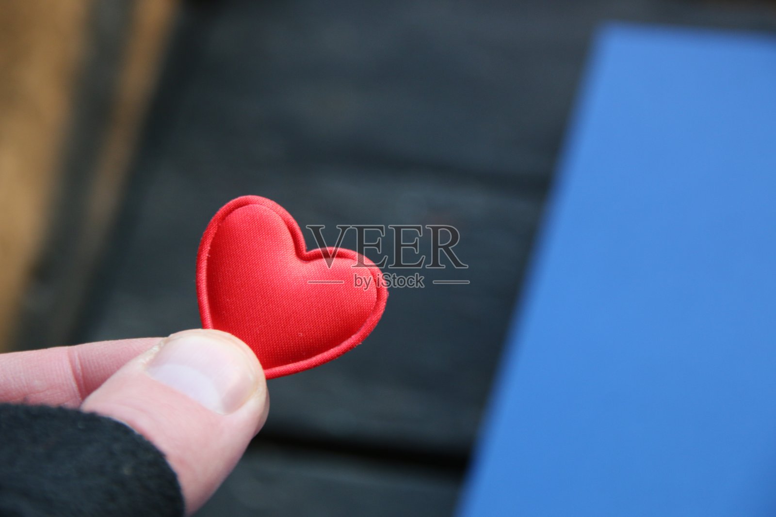 人的手握着红色的玩具心。情人节的主意。照片摄影图片