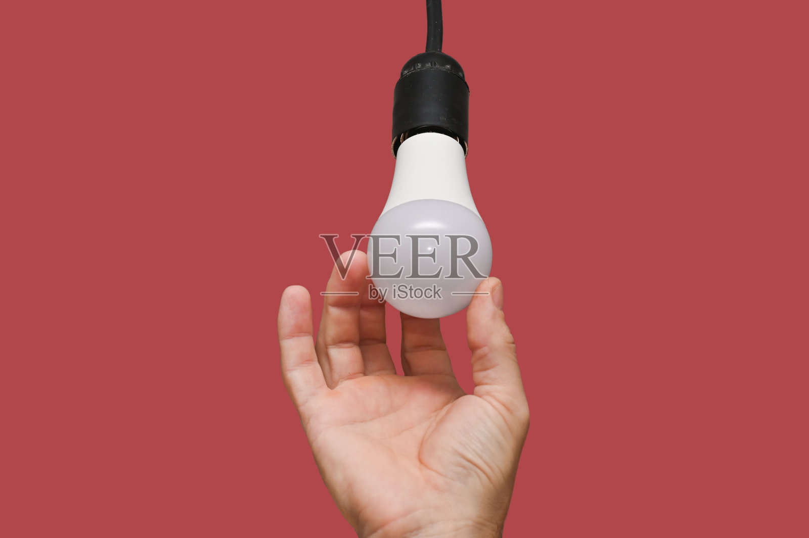 用手把LED灯拧进墨盒。孤立的照片摄影图片