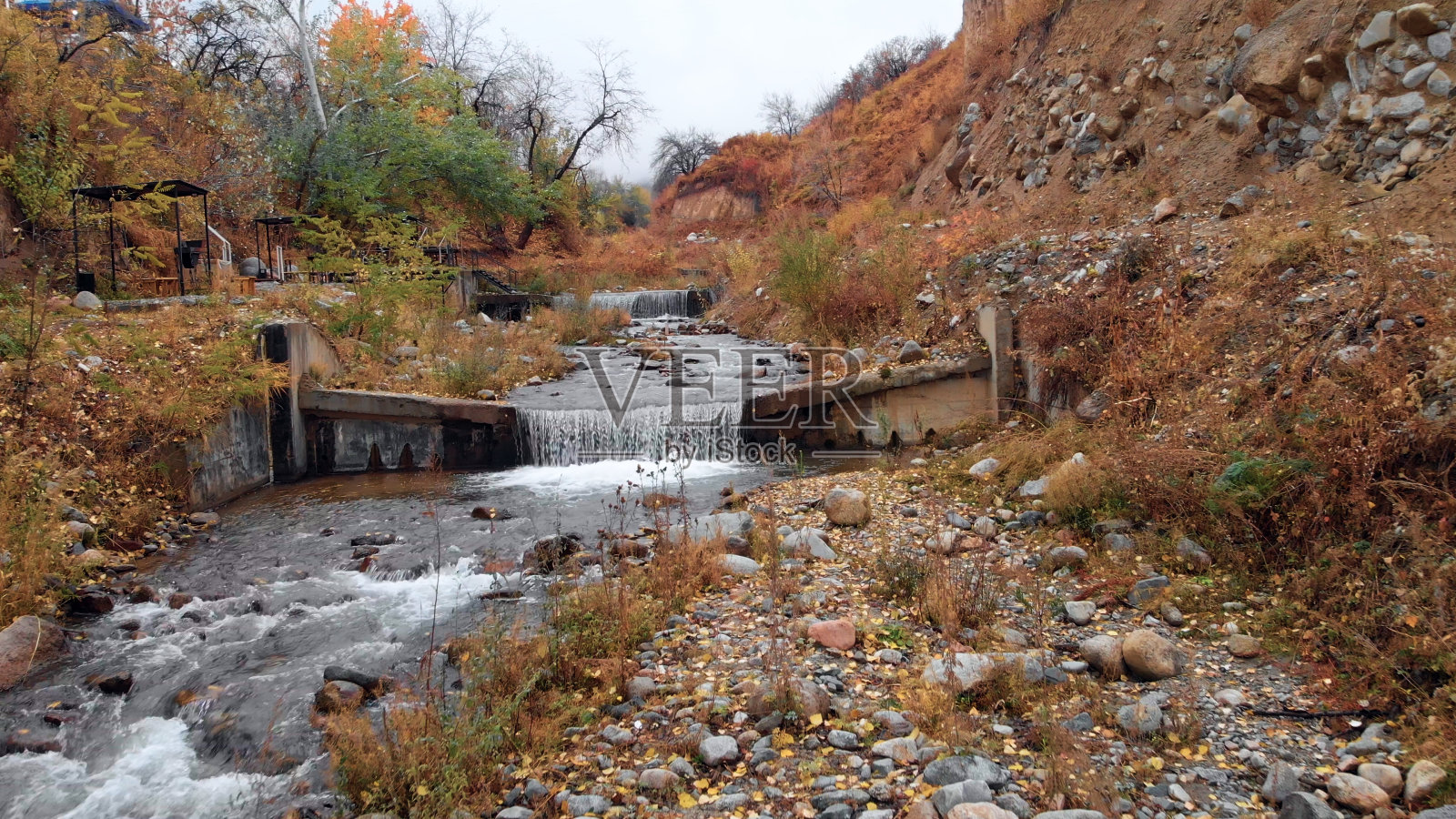 秋天在山河上的电影飞行。山区河流层层叠叠，秋色环绕。无人机在河流上空飞行，从一个小瀑布上方迅速倾泻而下照片摄影图片