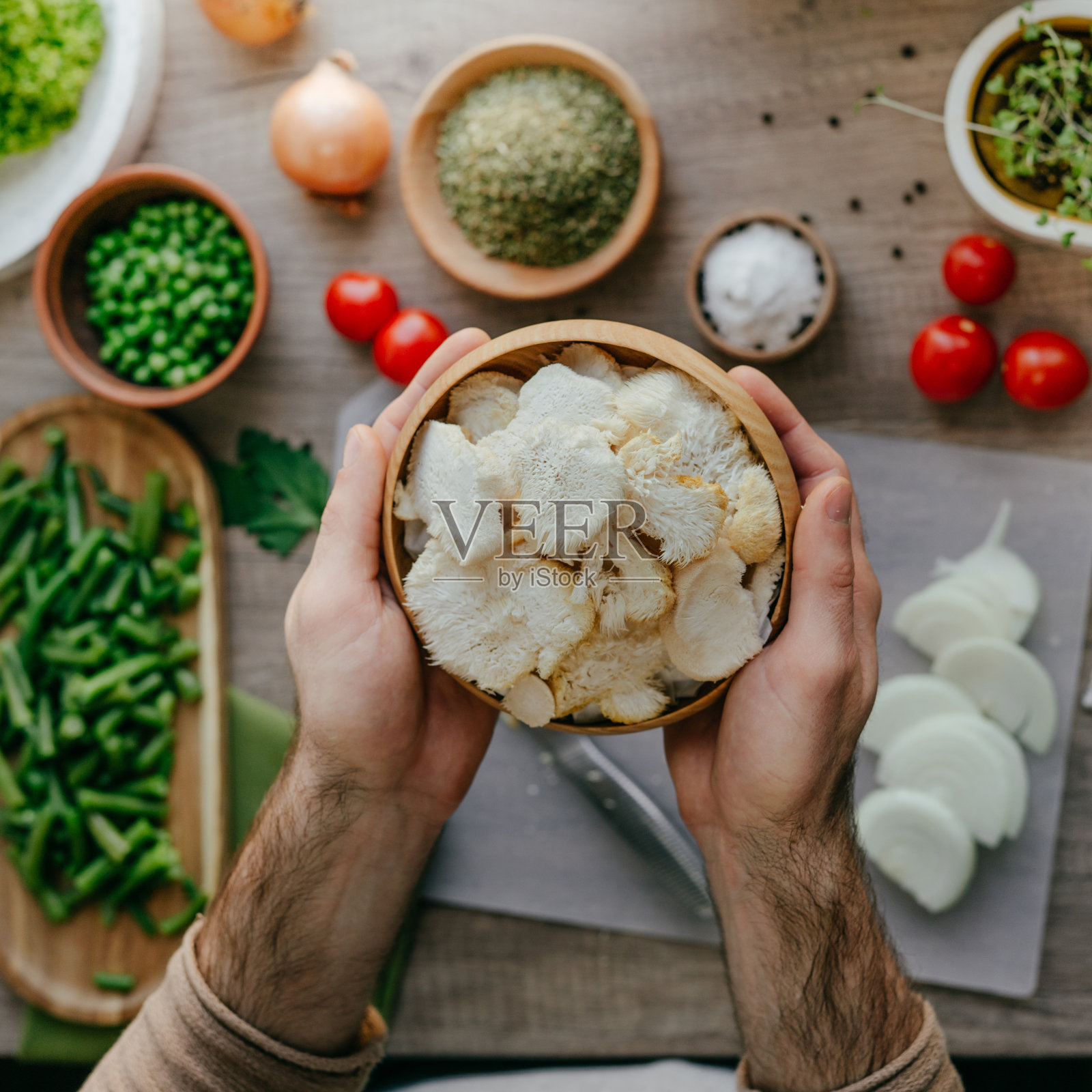 特写男性手拿木盘切猴头菇照片摄影图片