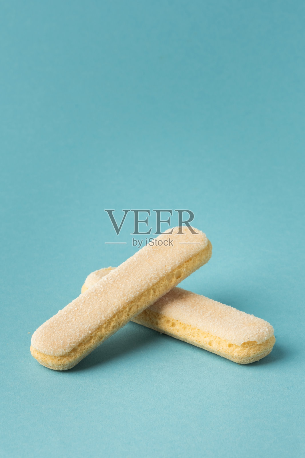 传统的意大利萨瓦亚尔迪手指饼干堆叠在一起的蓝色粉彩背景。一堆甜海绵饼干配提拉米苏蛋糕照片摄影图片