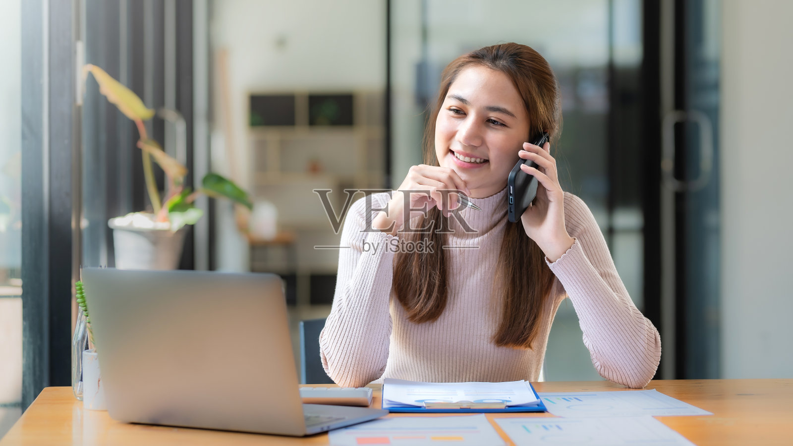 美丽的微笑年轻的亚洲女商人在工作中打电话。照片摄影图片