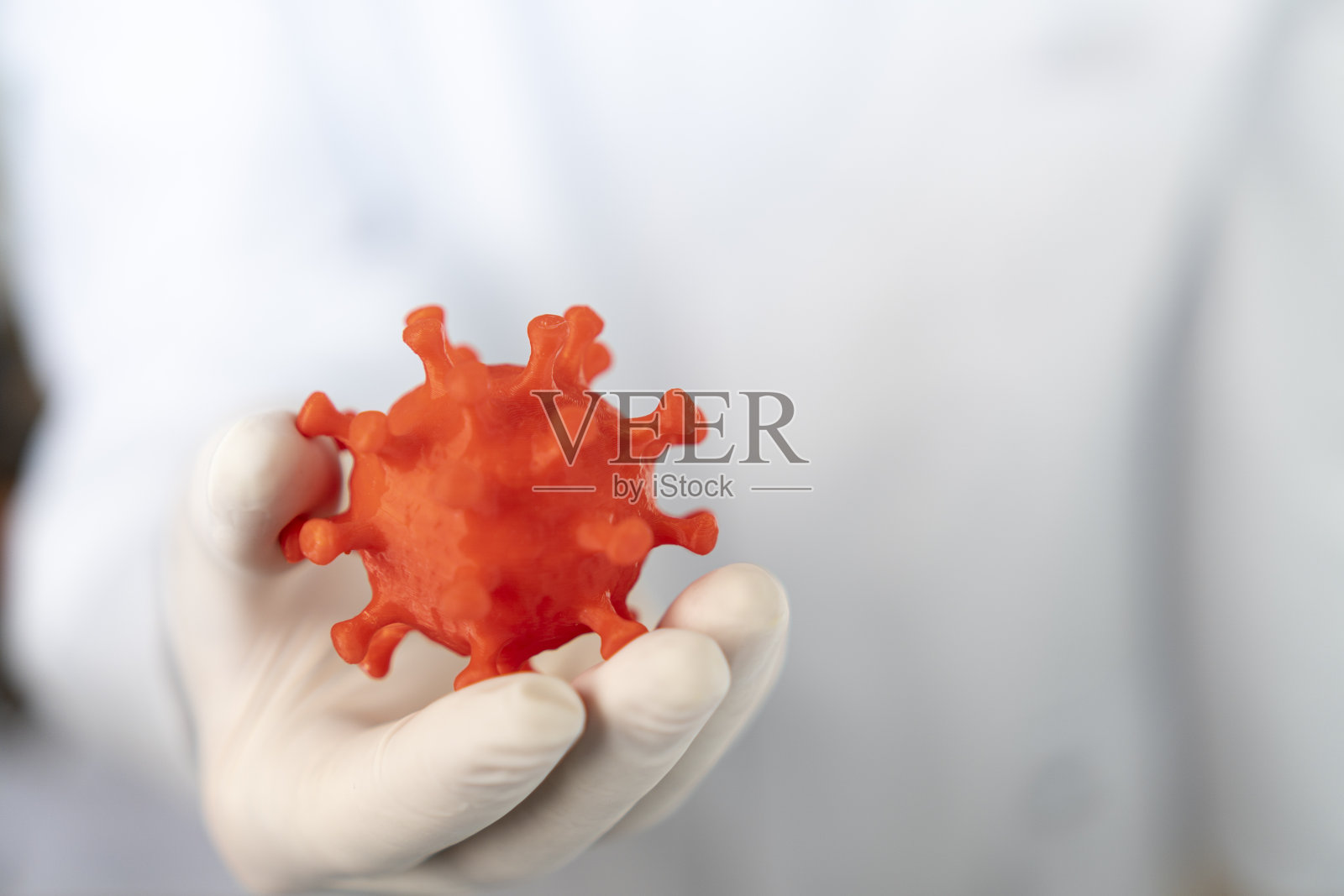 戴口罩的男性科学家或病毒学家手持covid-19冠状病毒3d模型照片摄影图片