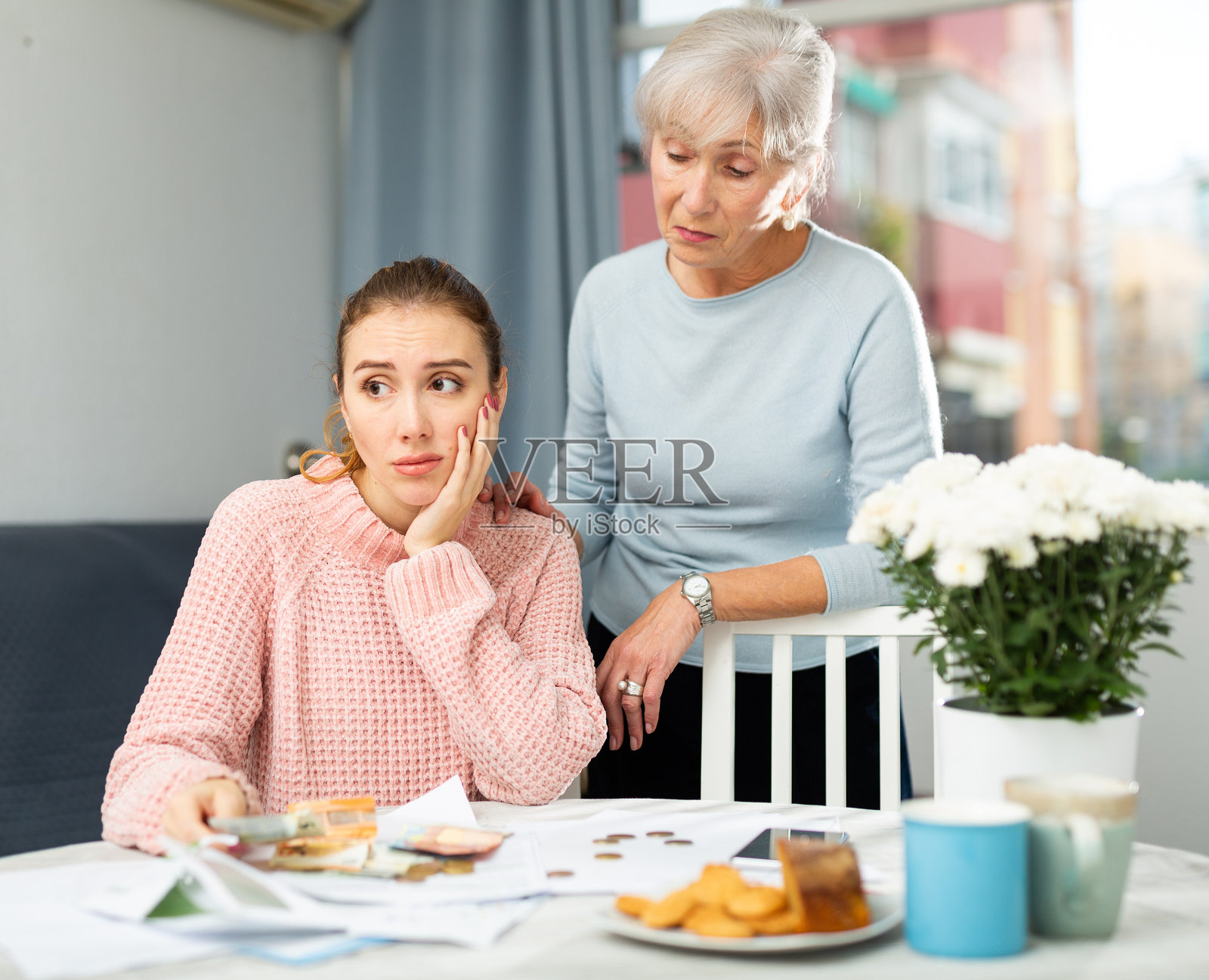 心烦意乱的年轻女子与年迈的母亲计算家务琐事的运行成本照片摄影图片