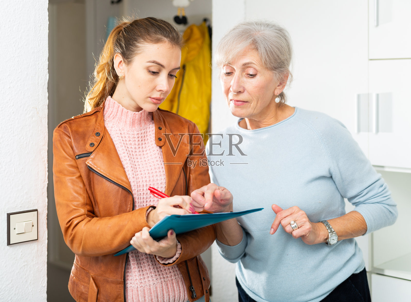 年长的女士和年轻的妇女在家里填写文件照片摄影图片