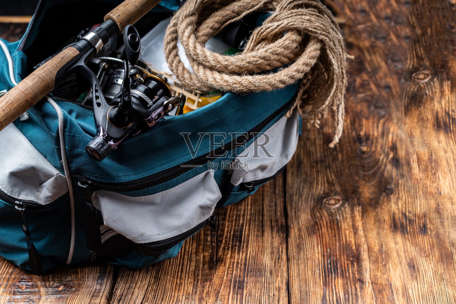 装有钓鱼物品的钓鱼袋。带卷轴和钓具袋的钓竿。钓鱼组成。照片摄影图片