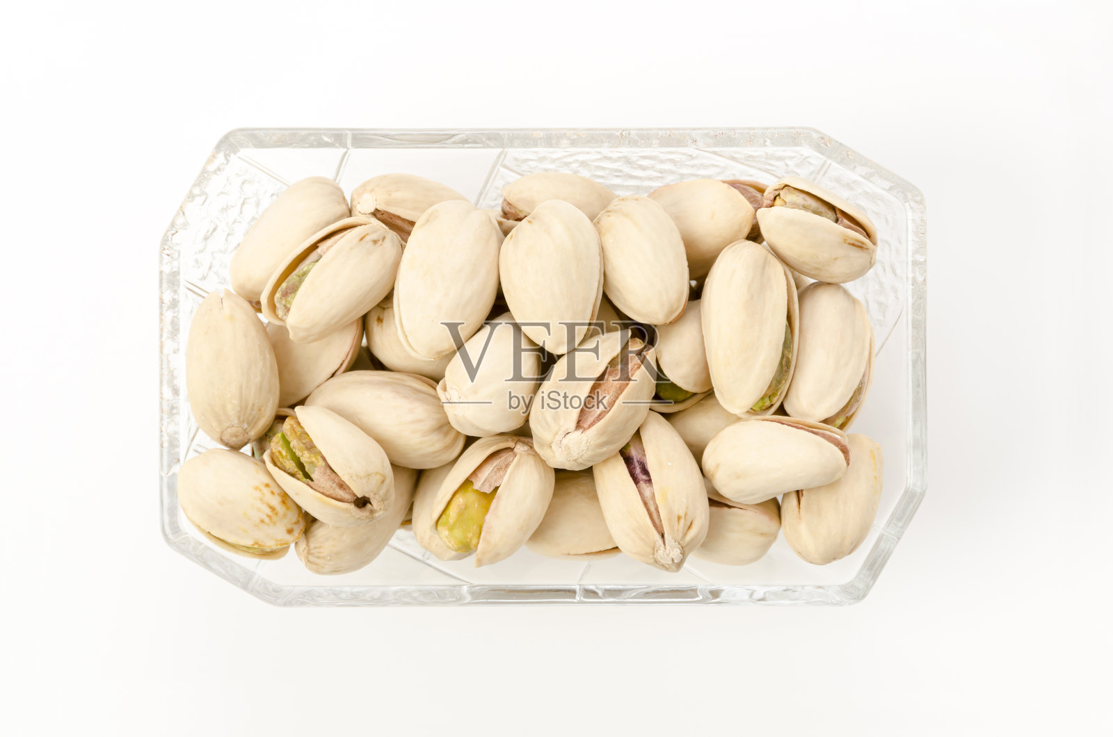 开心果放在白色背景的方形玻璃碗里照片摄影图片