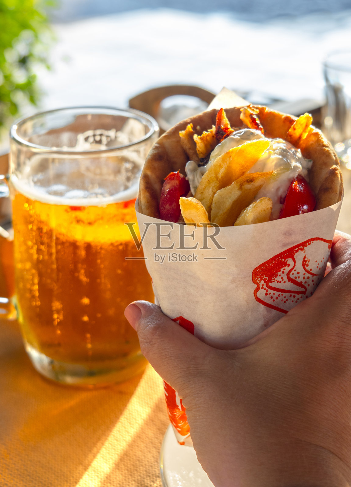 希腊肉圆饼，薯条，番茄，洋葱皮塔饼，手拿一杯希腊啤酒照片摄影图片