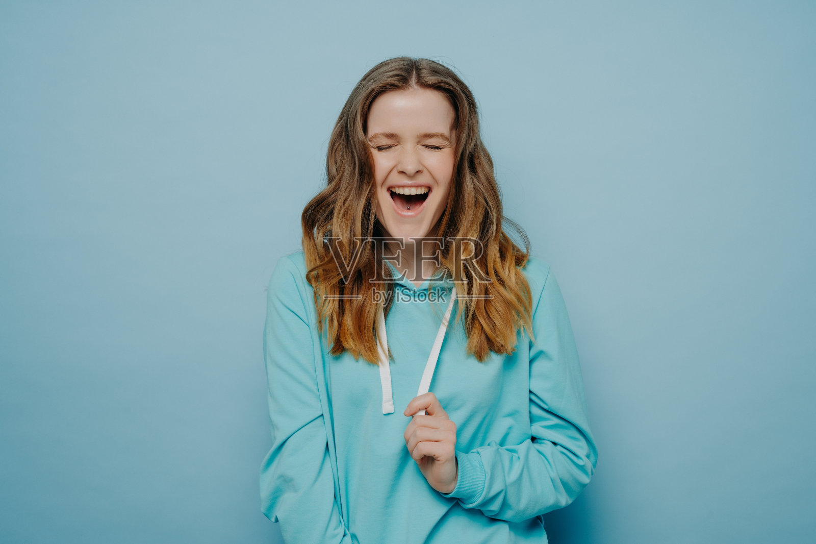 演播室里闭着眼睛笑得很开心的漂亮少女照片摄影图片